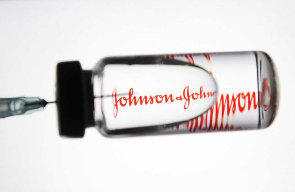 In this photo illustration a medical syringe and a vial with
