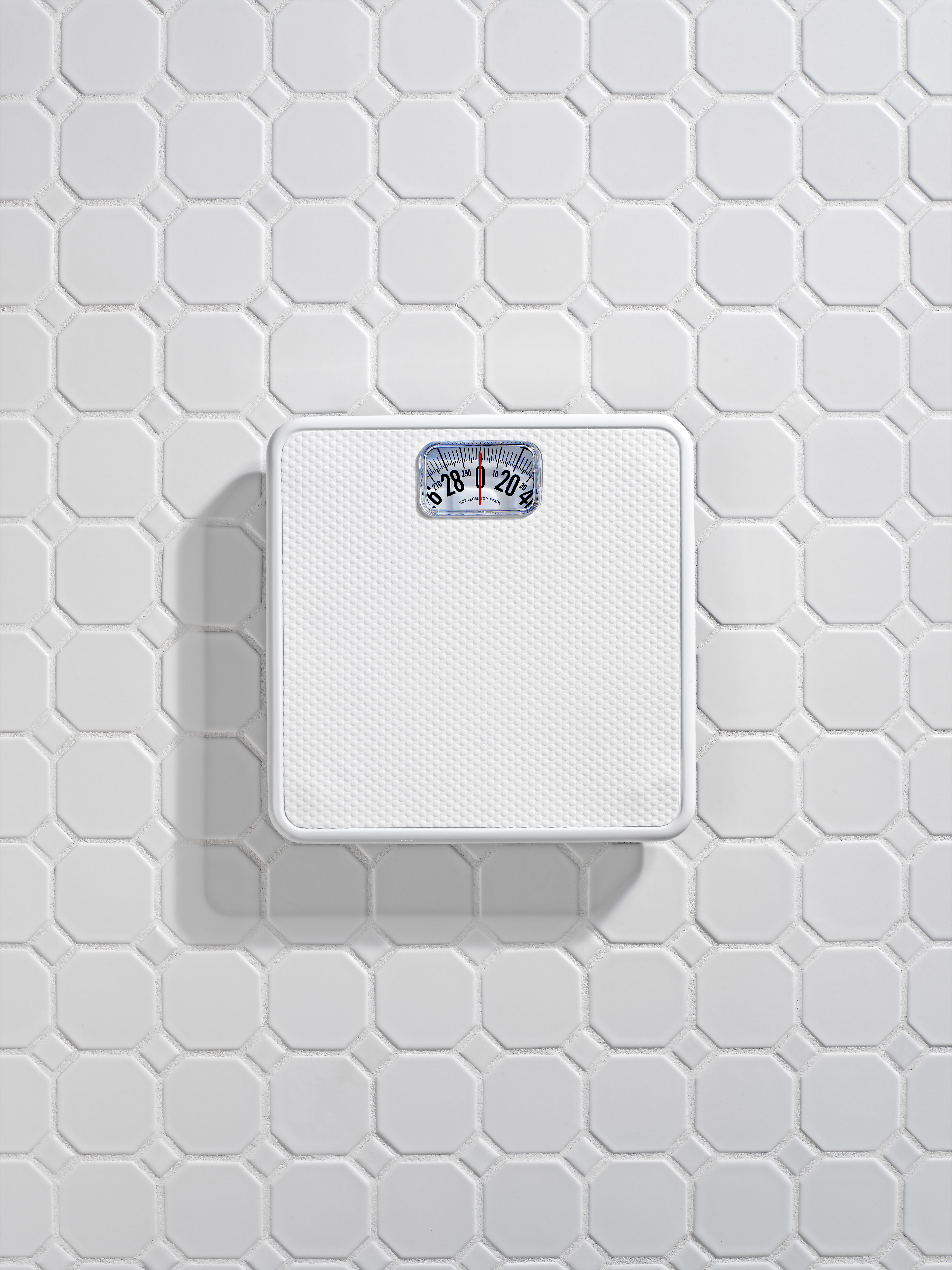 Bathroom scale on white tile floor.