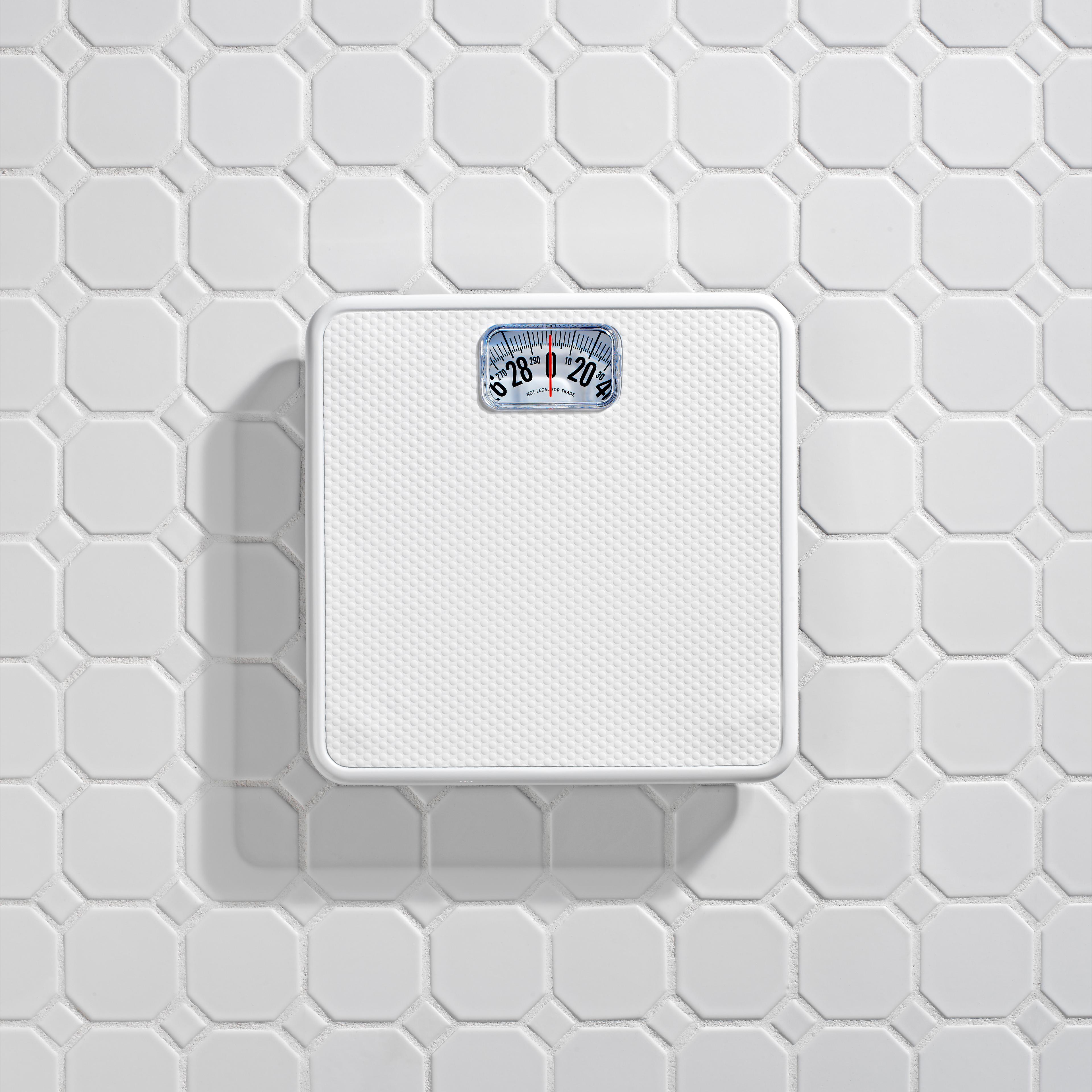 Bathroom scale on white tile floor.