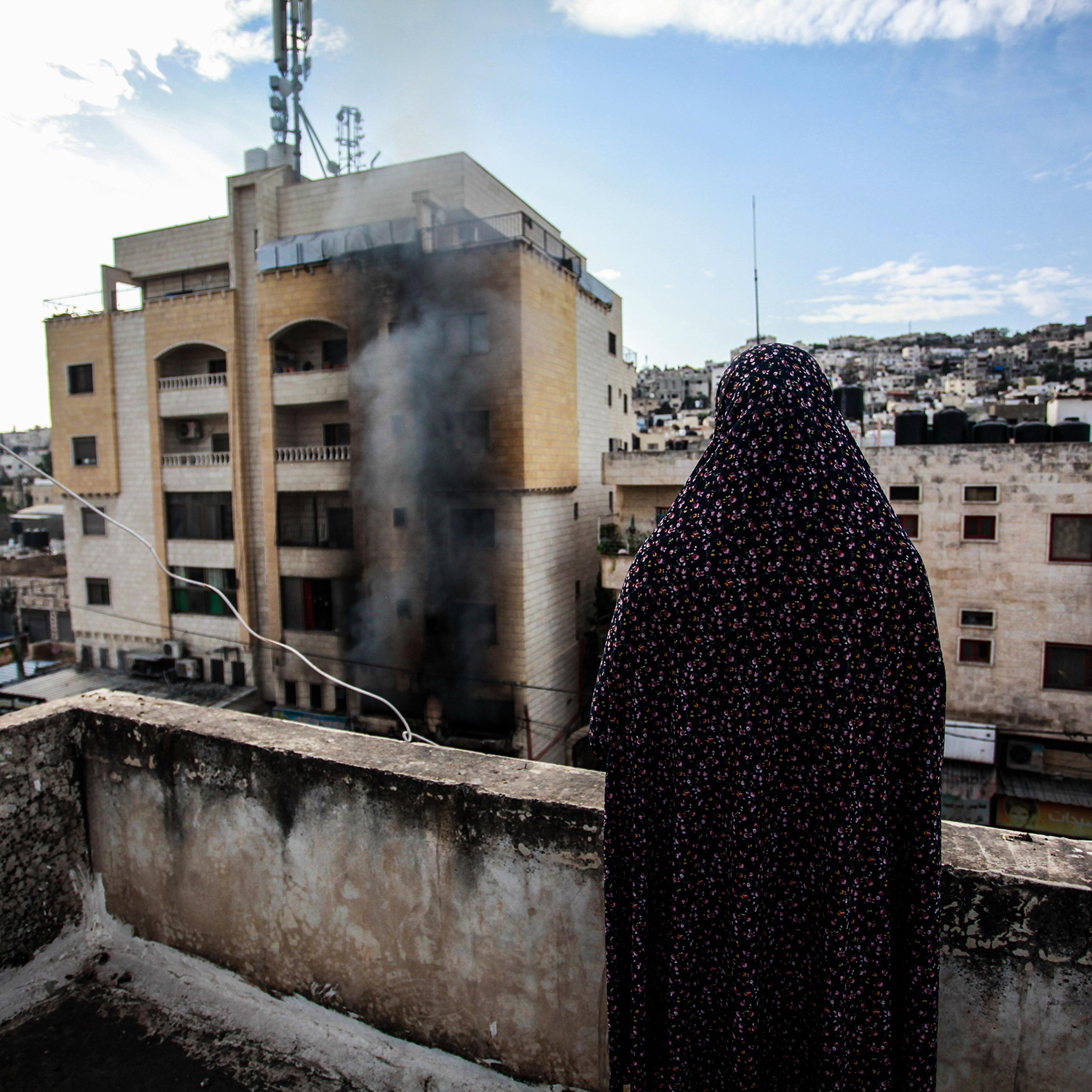 A Palestinian woman looks at a destroyed building following an Israeli military raid on the Jenin Palestinian refugee camp on Oct. 30.