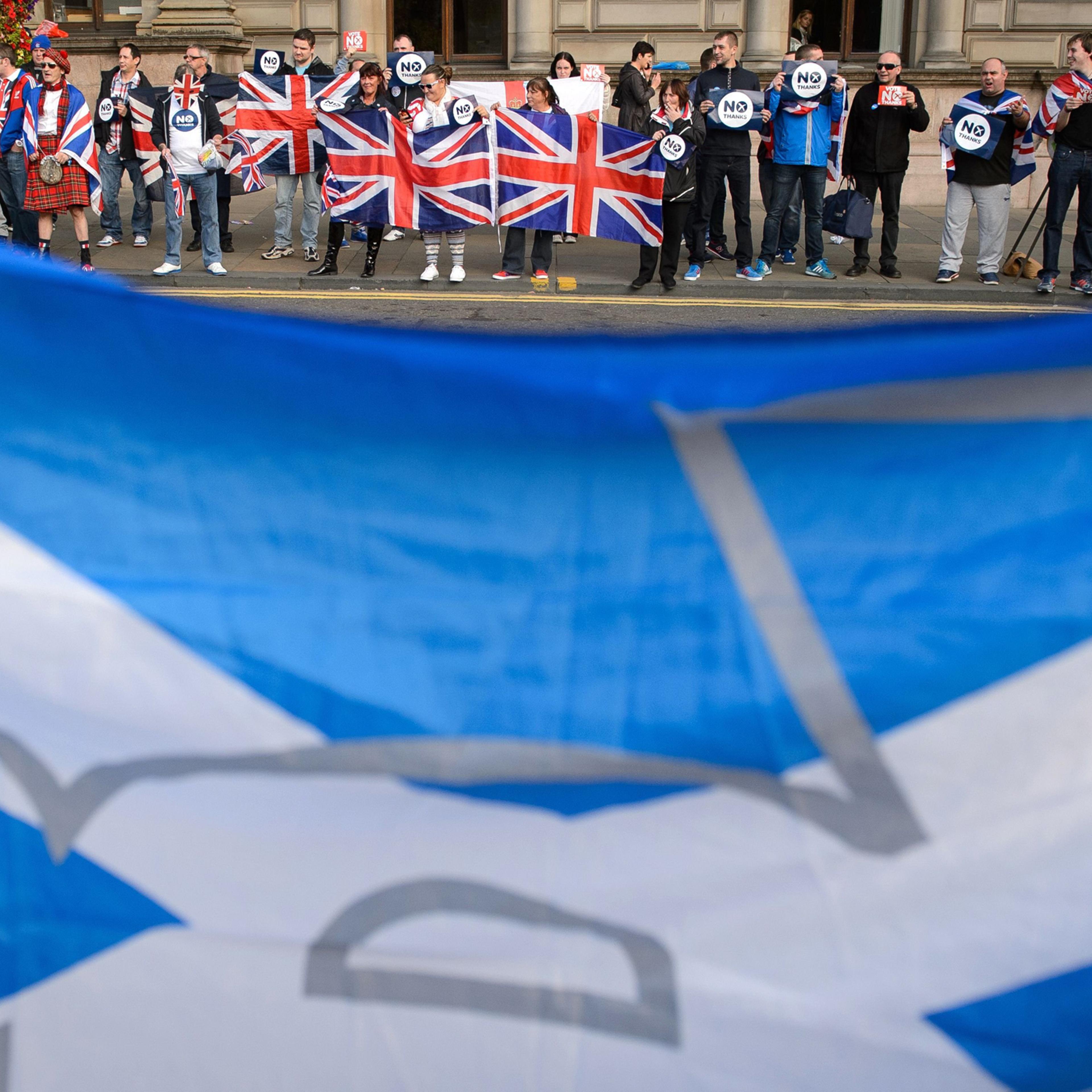 Pro-independence supporters' Scottish flag seen in front pro-union activists in Glasgow's George Square, in Scotland, on Sept. 17, 2014, on the eve of Scotland's independence referendum.
