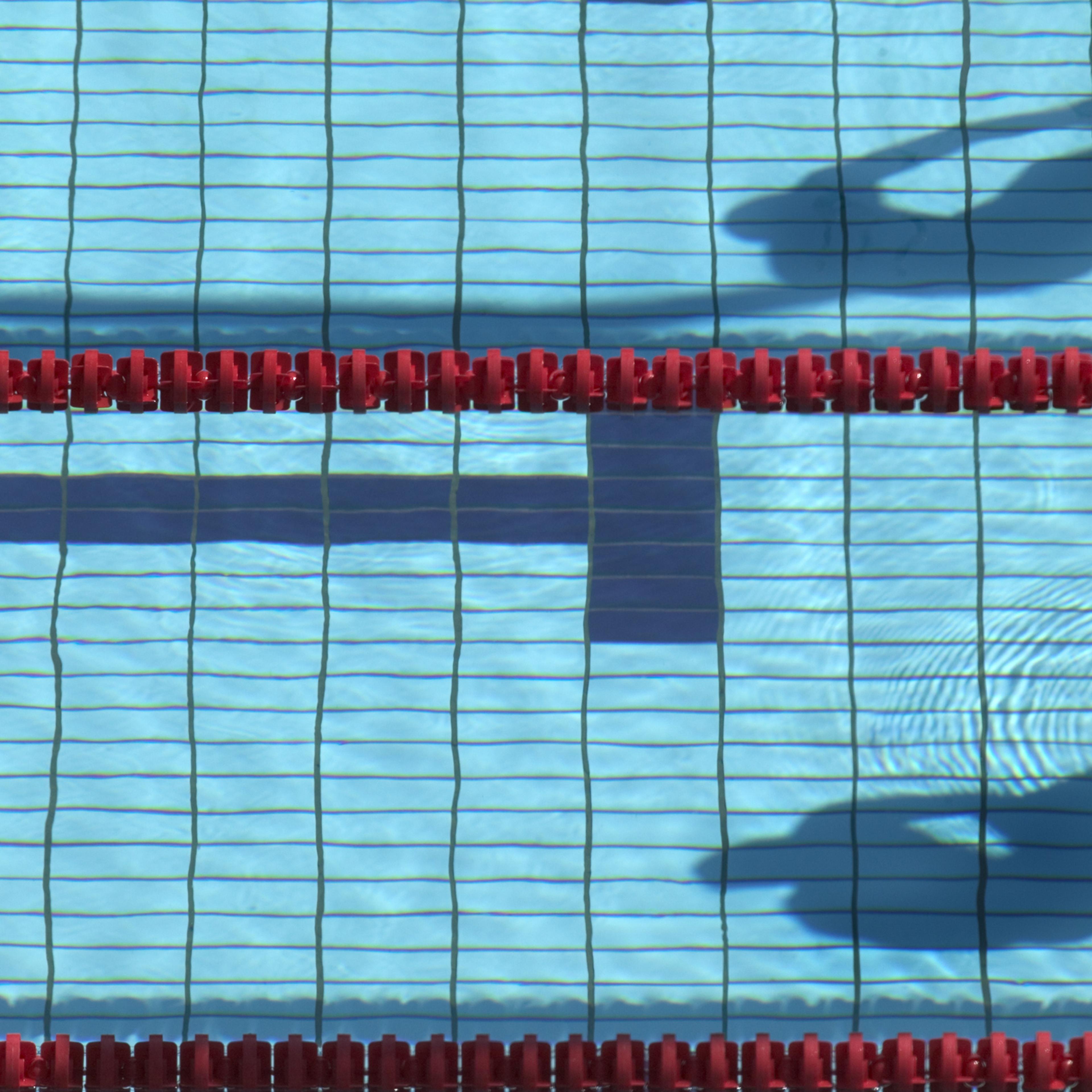 Shadow in swimming pool of swimmers on starting blocks