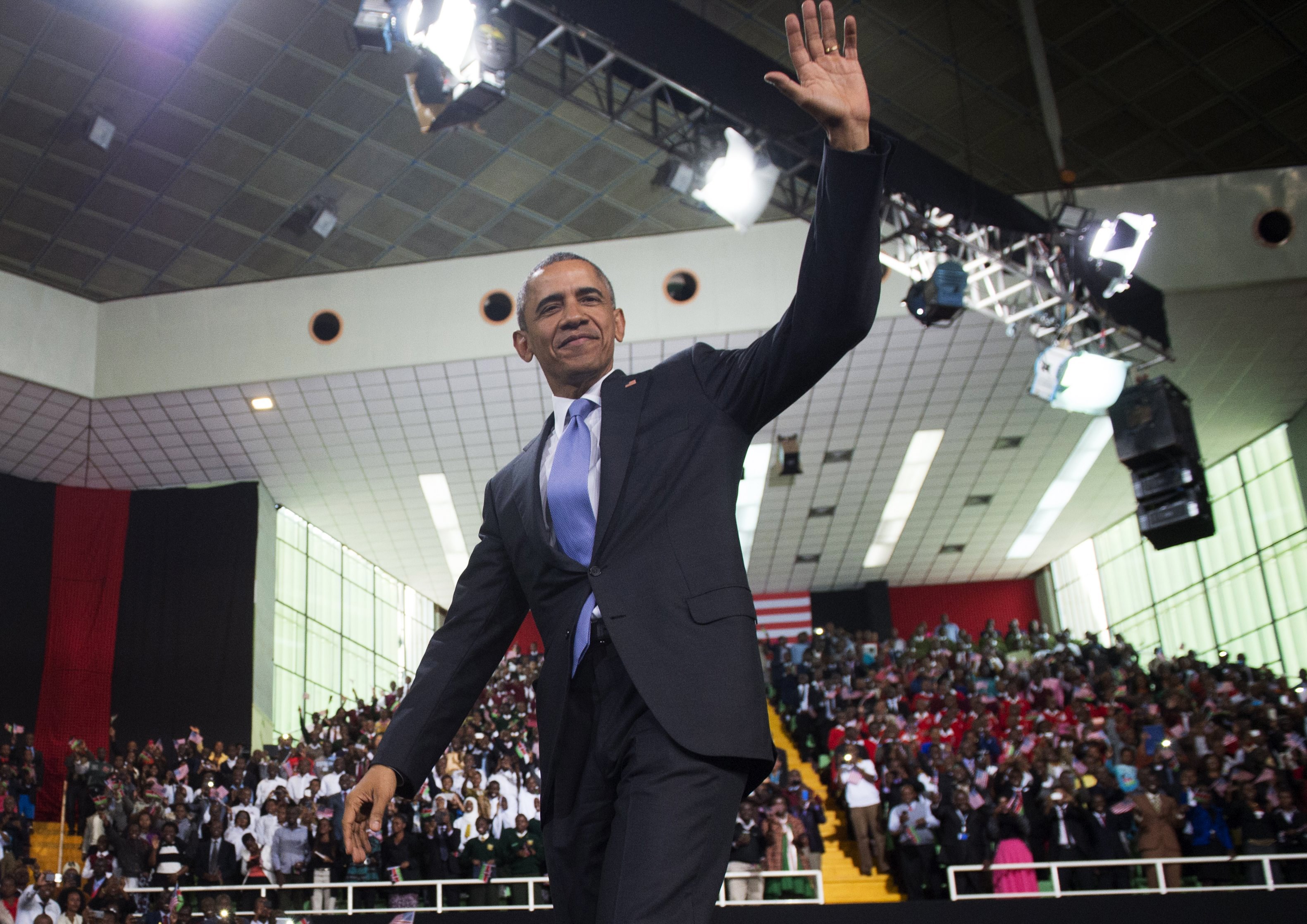 Barack Obama waves to a crowd at an indoor arena