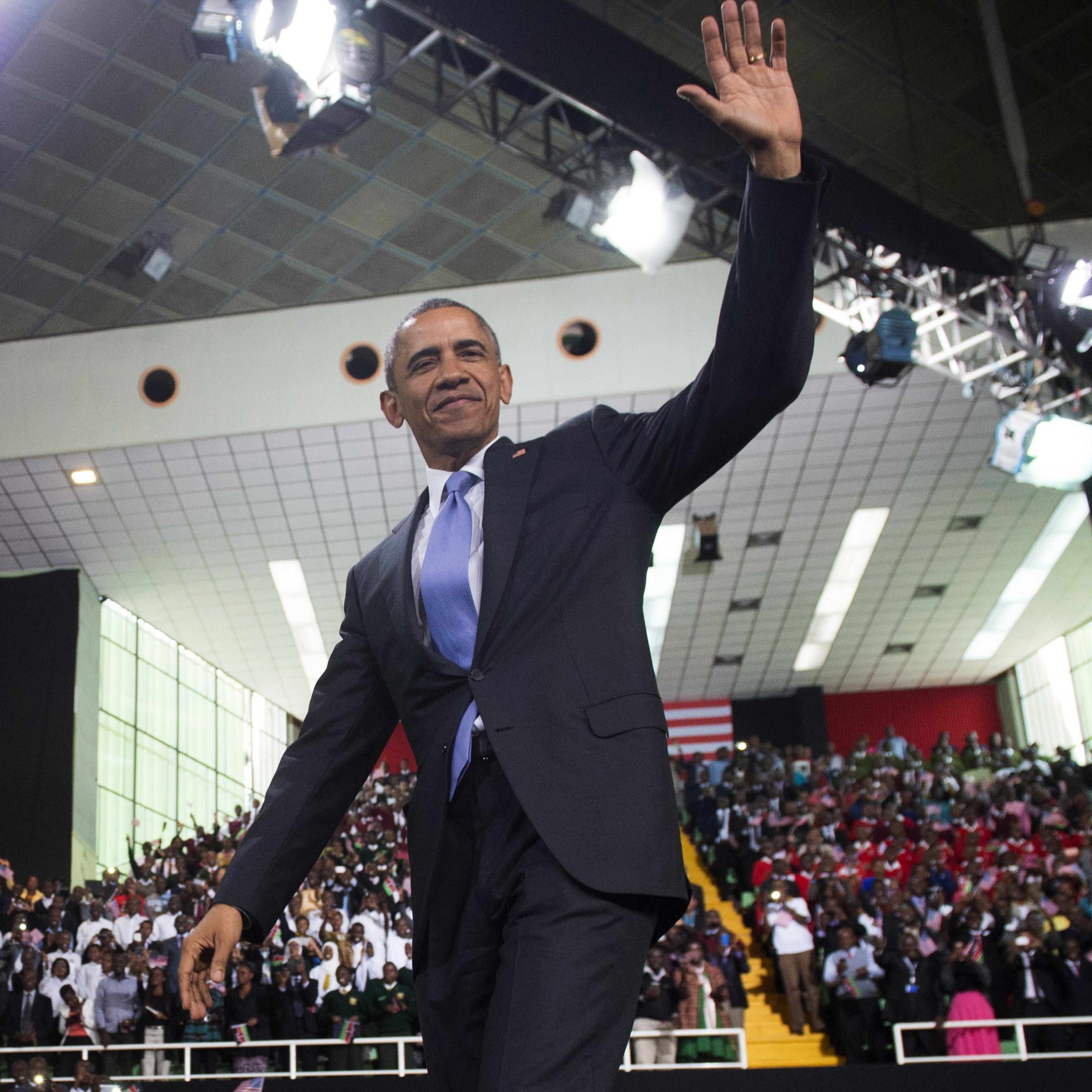Barack Obama waves to a crowd at an indoor arena