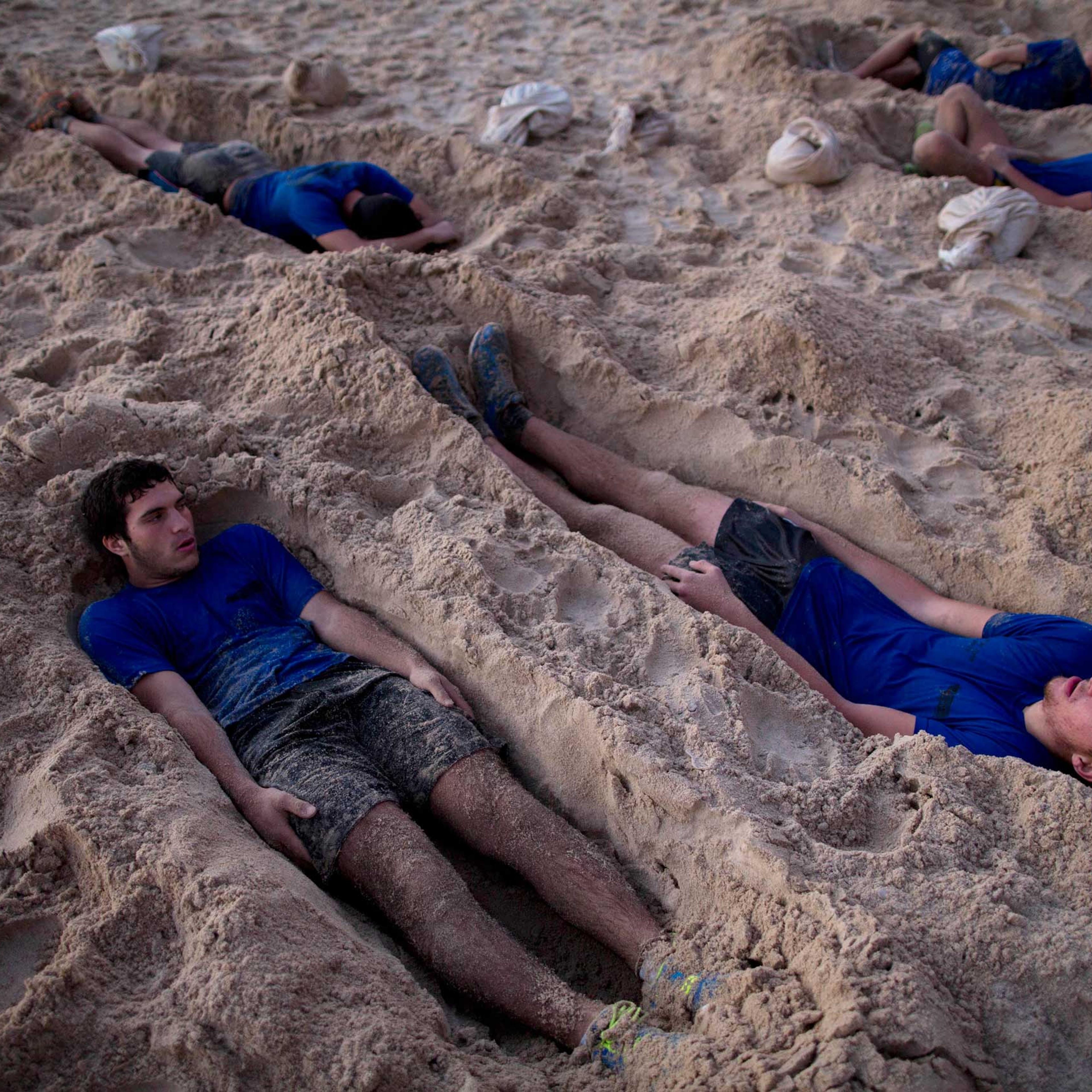 High-school seniors preparing to join the Israeli military later this year lie in foxholes during training in Shefayim, central Israel, March 5, 2015.