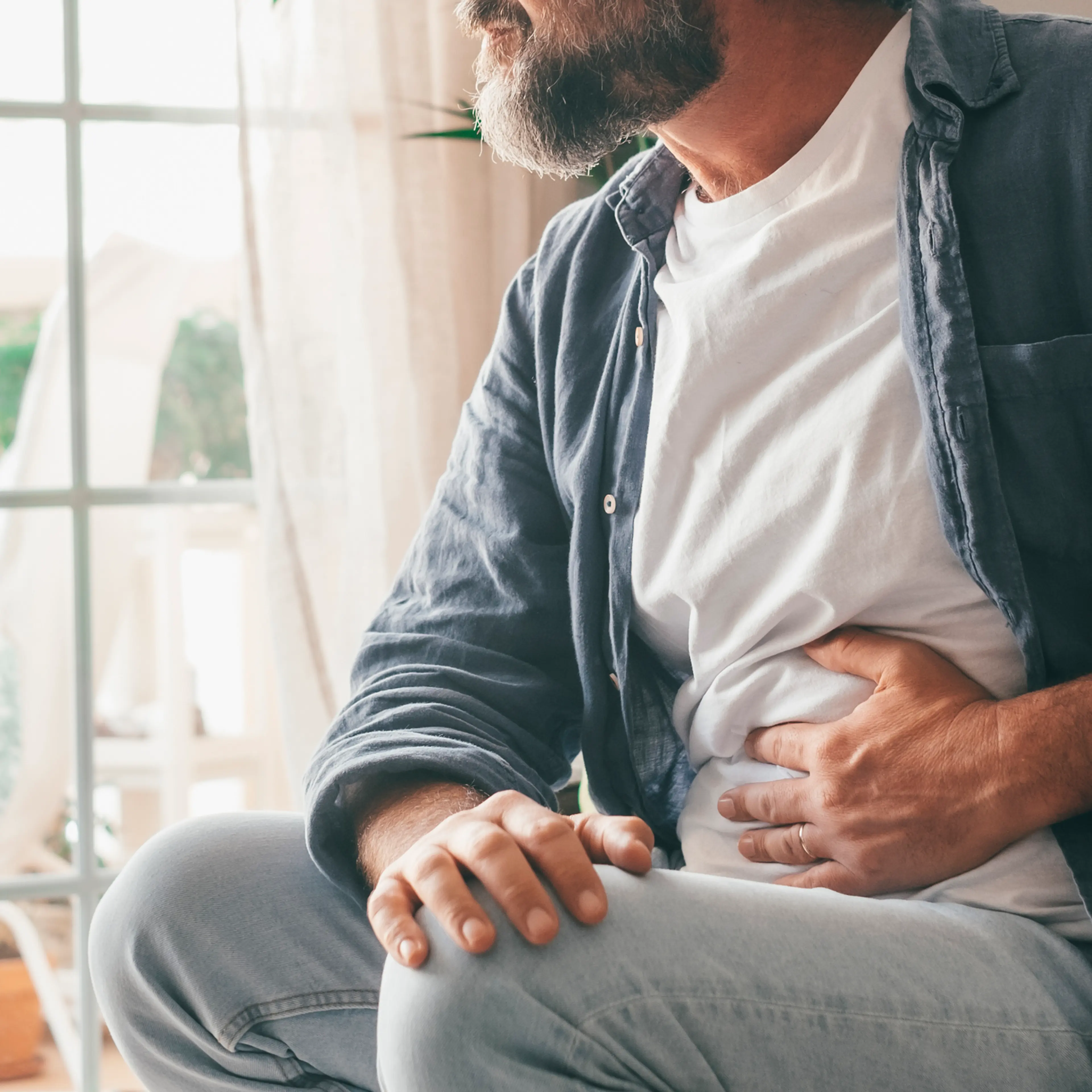 Midsection Of Man Touching Stomach At Home