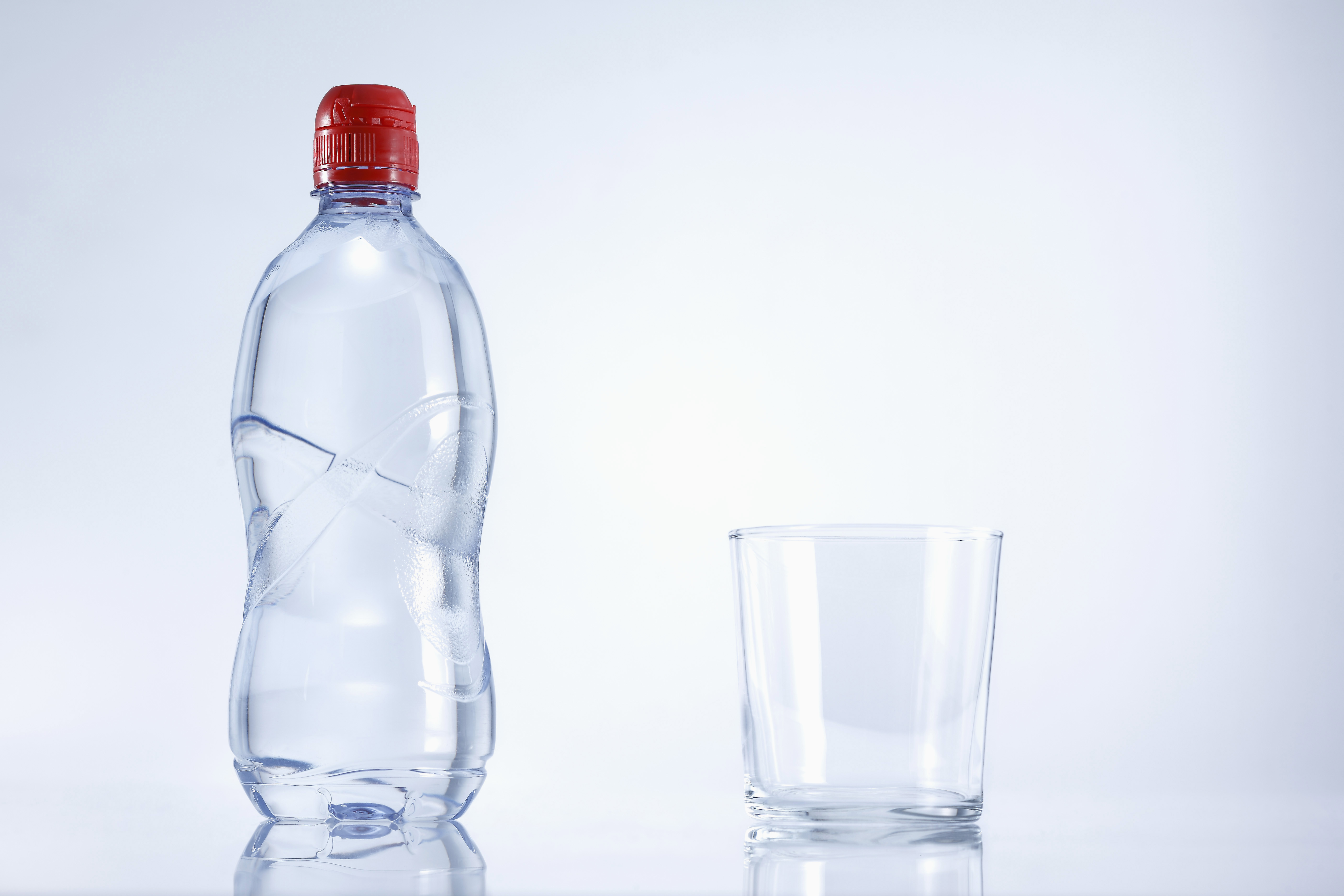 Plastic bottle of mineral water with glass, close up