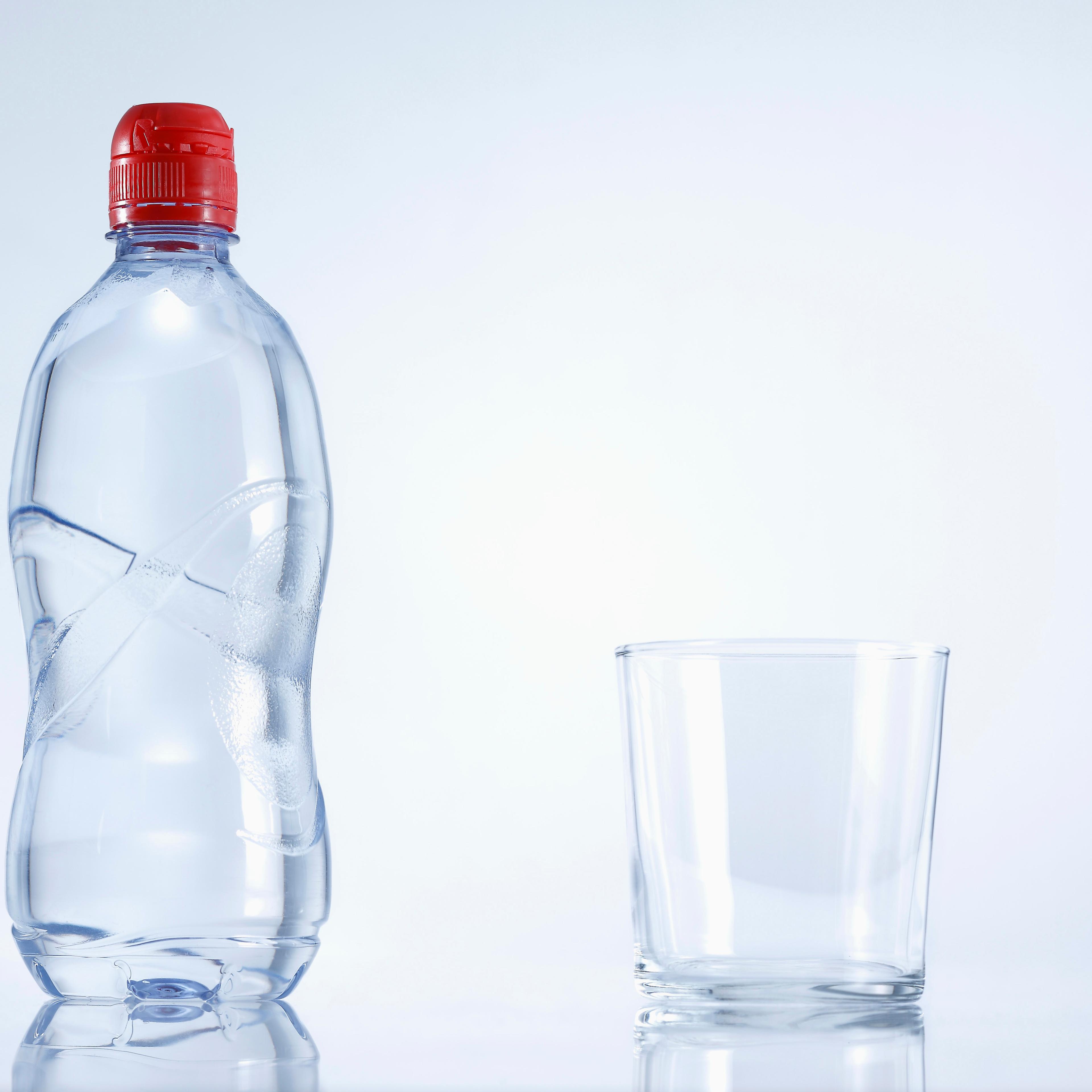 Plastic bottle of mineral water with glass, close up