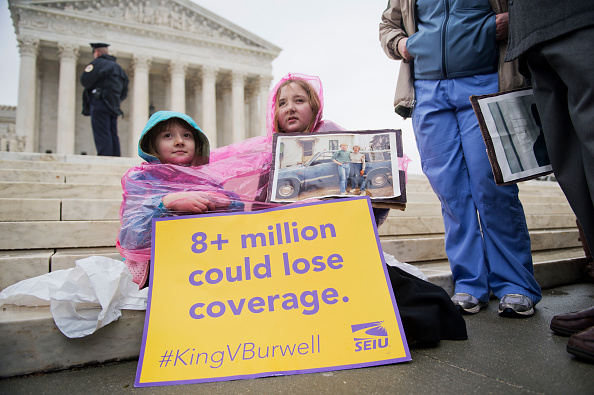 Cassie Boyle, 8, and her sister Helena Roberts, 11, of Pittsburgh, hold a picture of their father Ray Roberts and grandmother Hannah Brown, at a rally outside of the Supreme Court during arguments in the King v. Burwell case which deals with tax credits 