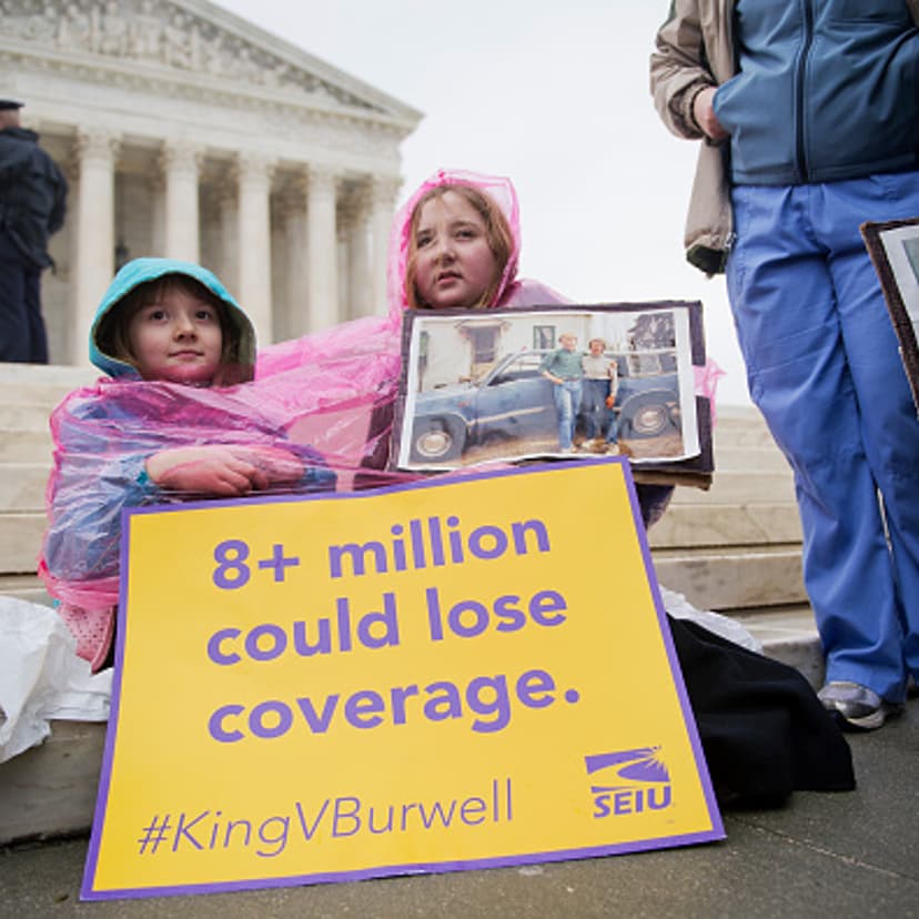 Cassie Boyle, 8, and her sister Helena Roberts, 11, of Pittsburgh, hold a picture of their father Ray Roberts and grandmother Hannah Brown, at a rally outside of the Supreme Court during arguments in the King v. Burwell case which deals with tax credits