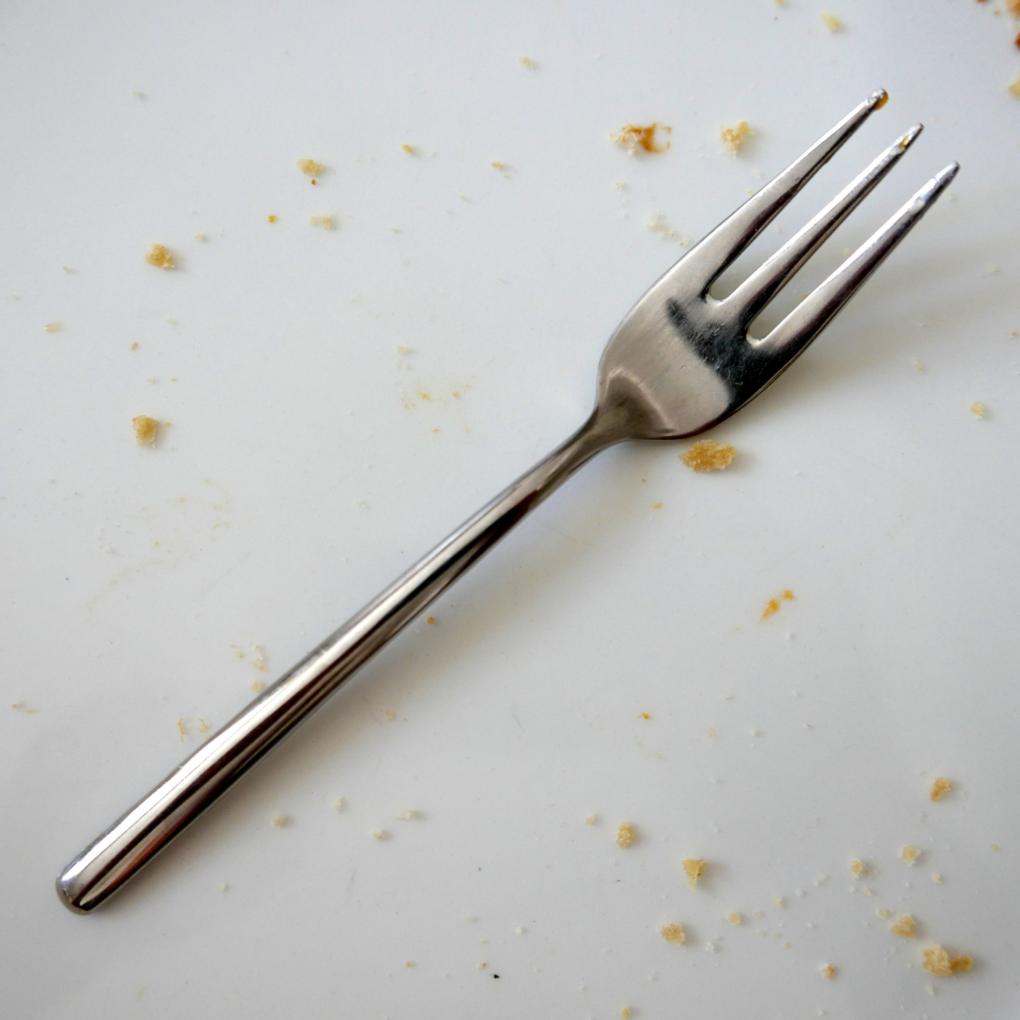 Close-Up Of Fork With Scattered Food Against White Background