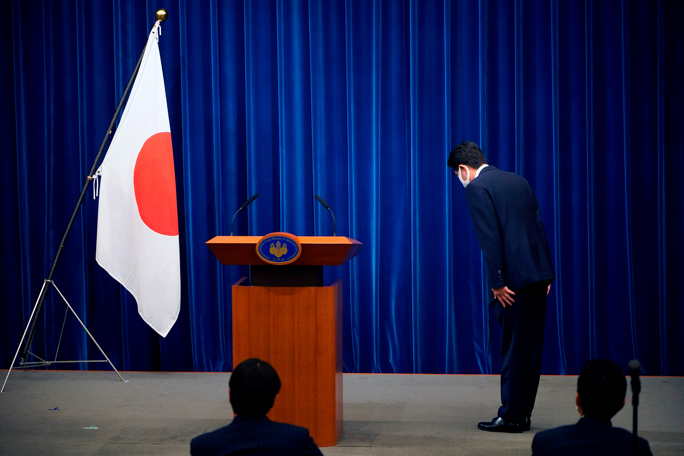Japanese Prime Minister Shinzo Abe bows to the national flag at the start of a press conference announcing he will resign over health problems on August 28, at the prime minister's official residence in Tokyo