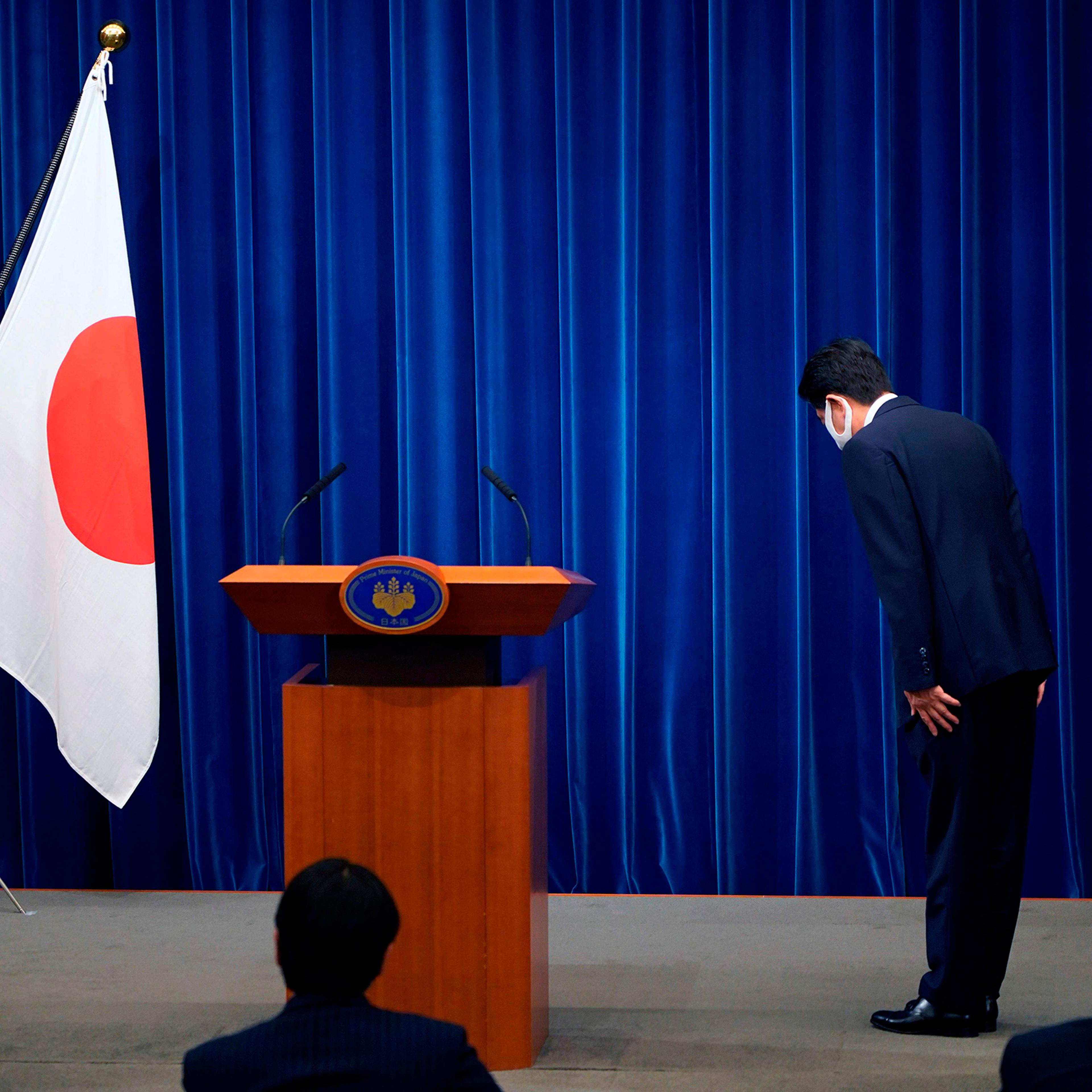 Japanese Prime Minister Shinzo Abe bows to the national flag at the start of a press conference announcing he will resign over health problems on August 28, at the prime minister's official residence in Tokyo