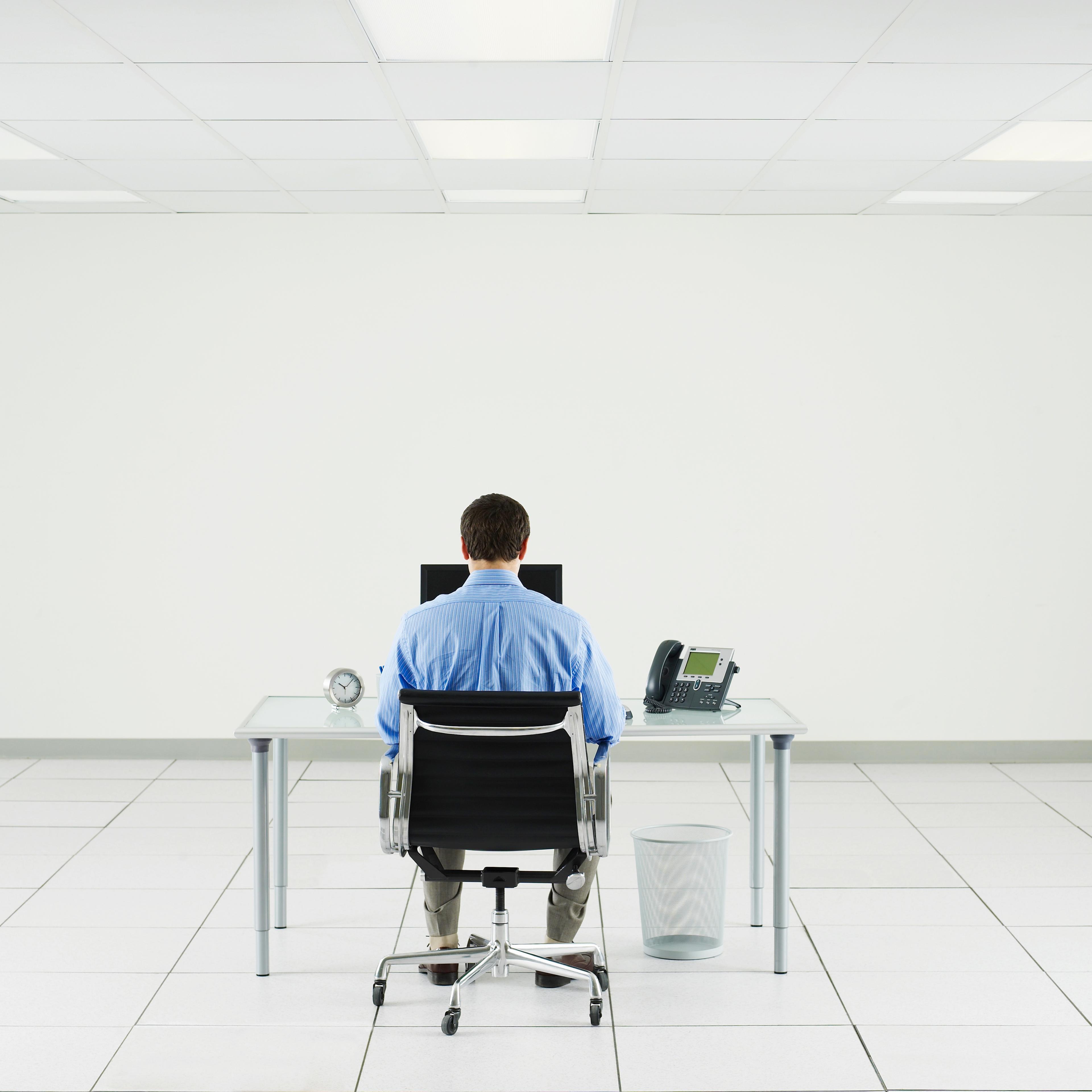 Man working at desk in empty room.