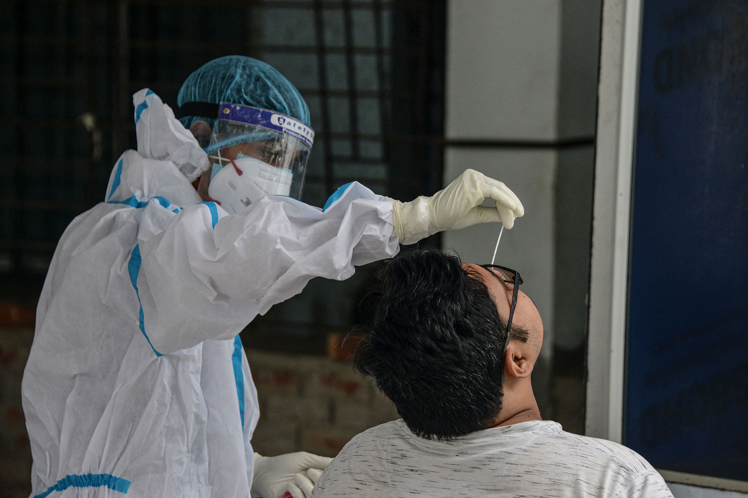 A health worker collects a swab sample for a RT-PCR COVID-19 test at the North Bengal Medical college and hospital on the outskirts of Siliguri on June 8, 2021