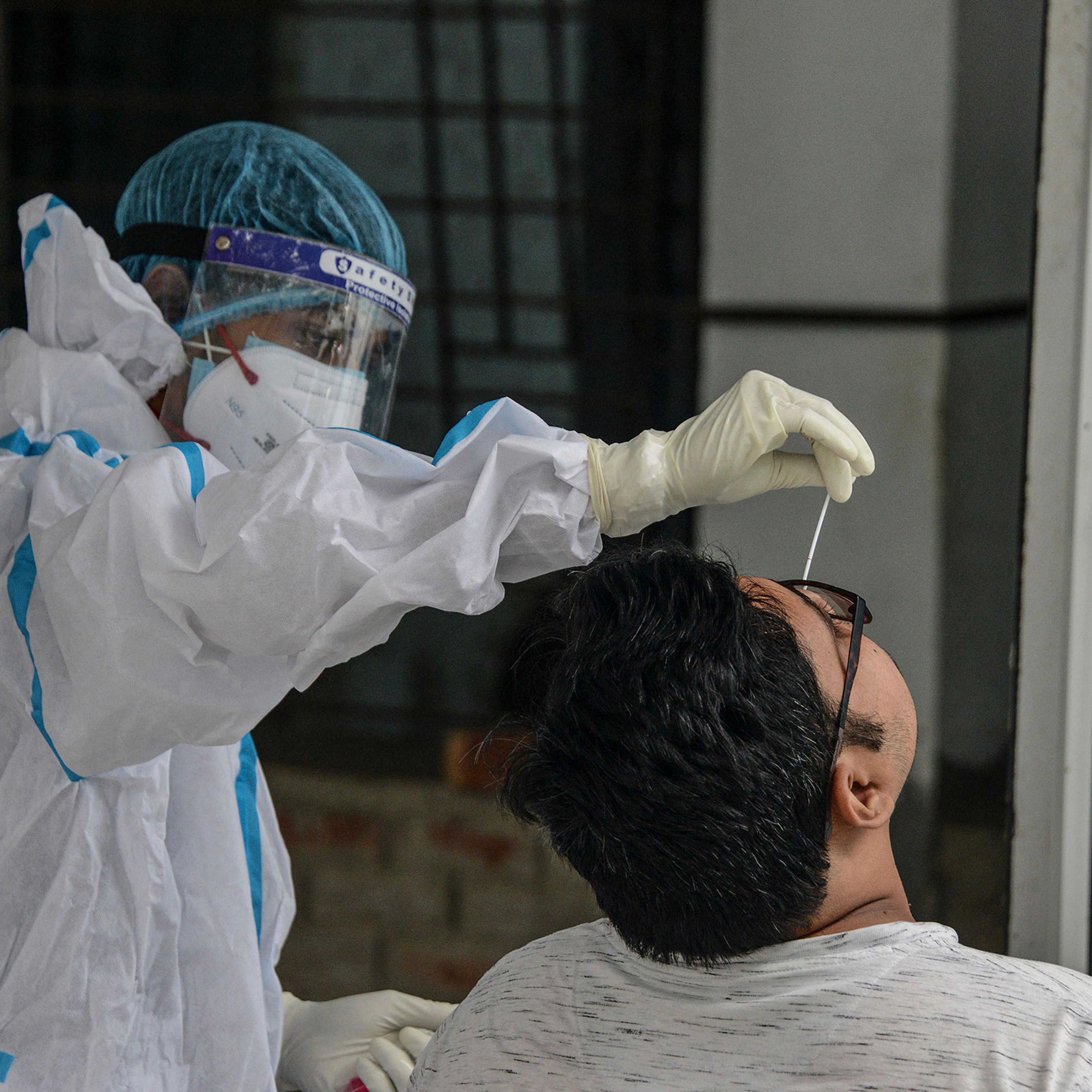 A health worker collects a swab sample for a RT-PCR COVID-19 test at the North Bengal Medical college and hospital on the outskirts of Siliguri on June 8, 2021