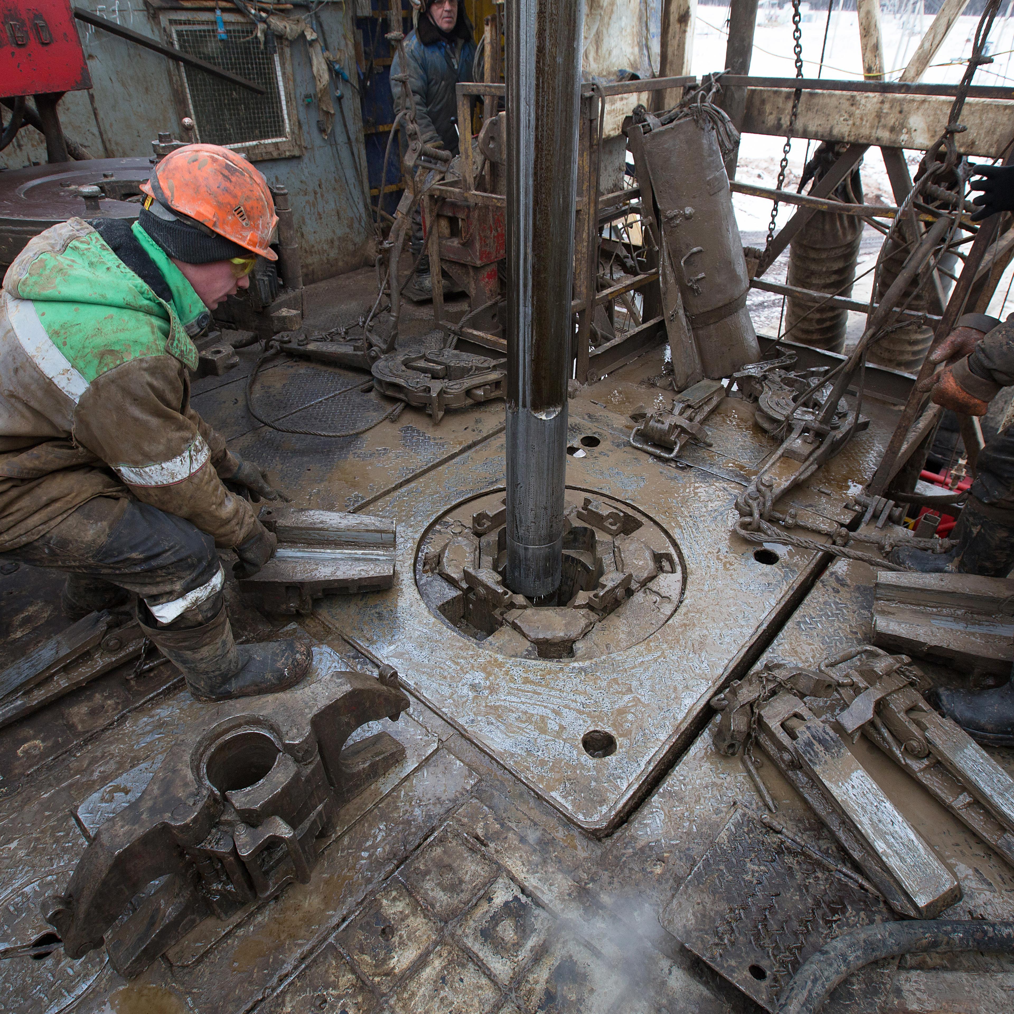 Oil workers adjust a pipe section at the turntable on an oil derrick during drilling operations by Targin JSC, a unit of Sistema JSFC, in an oilfield operated by Bashneft PAO in the village of Otrada, 150kms from Ufa, Russia, on Saturday, March 5, 2016.