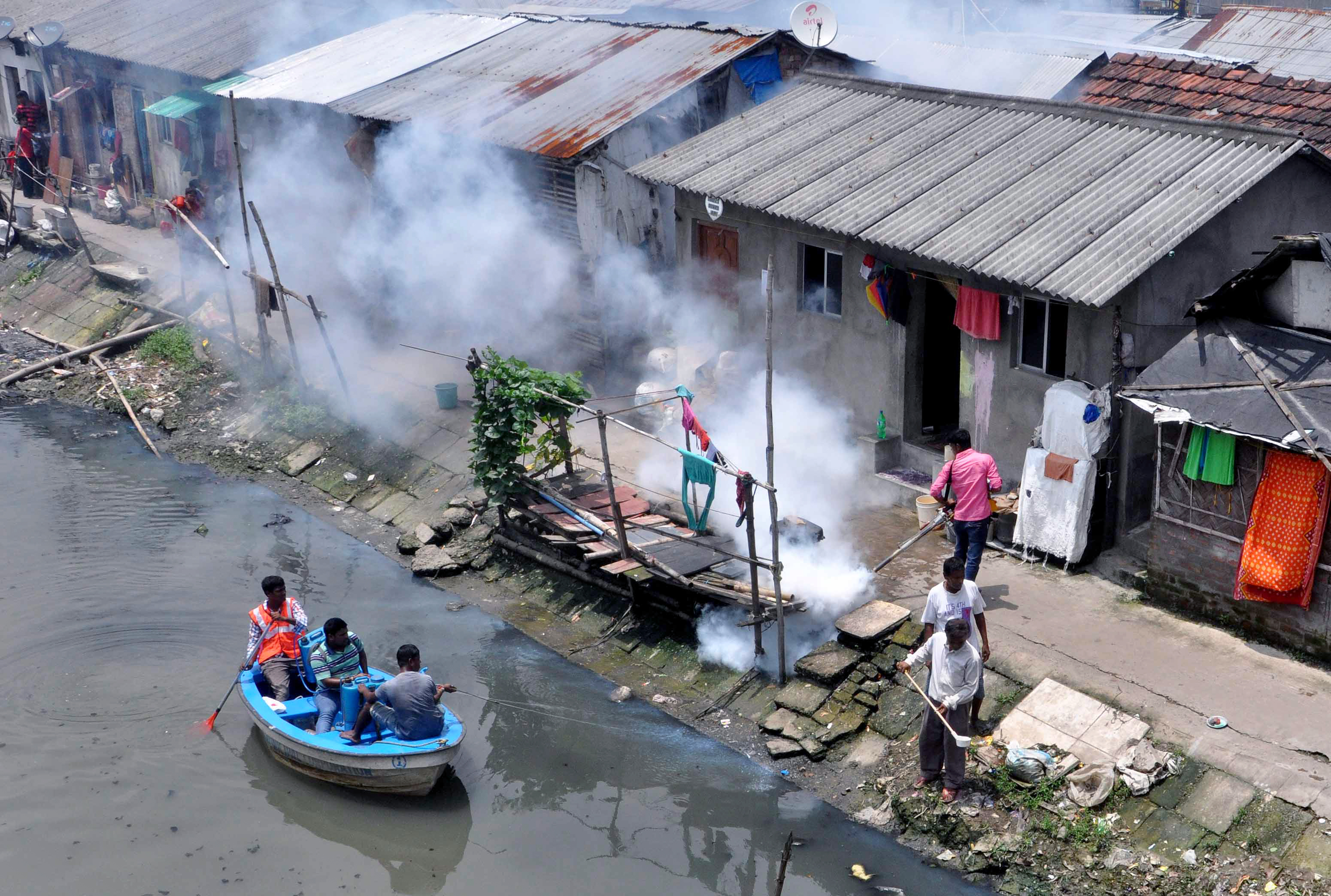 Municipal workers spray chemicals in canal and other worker