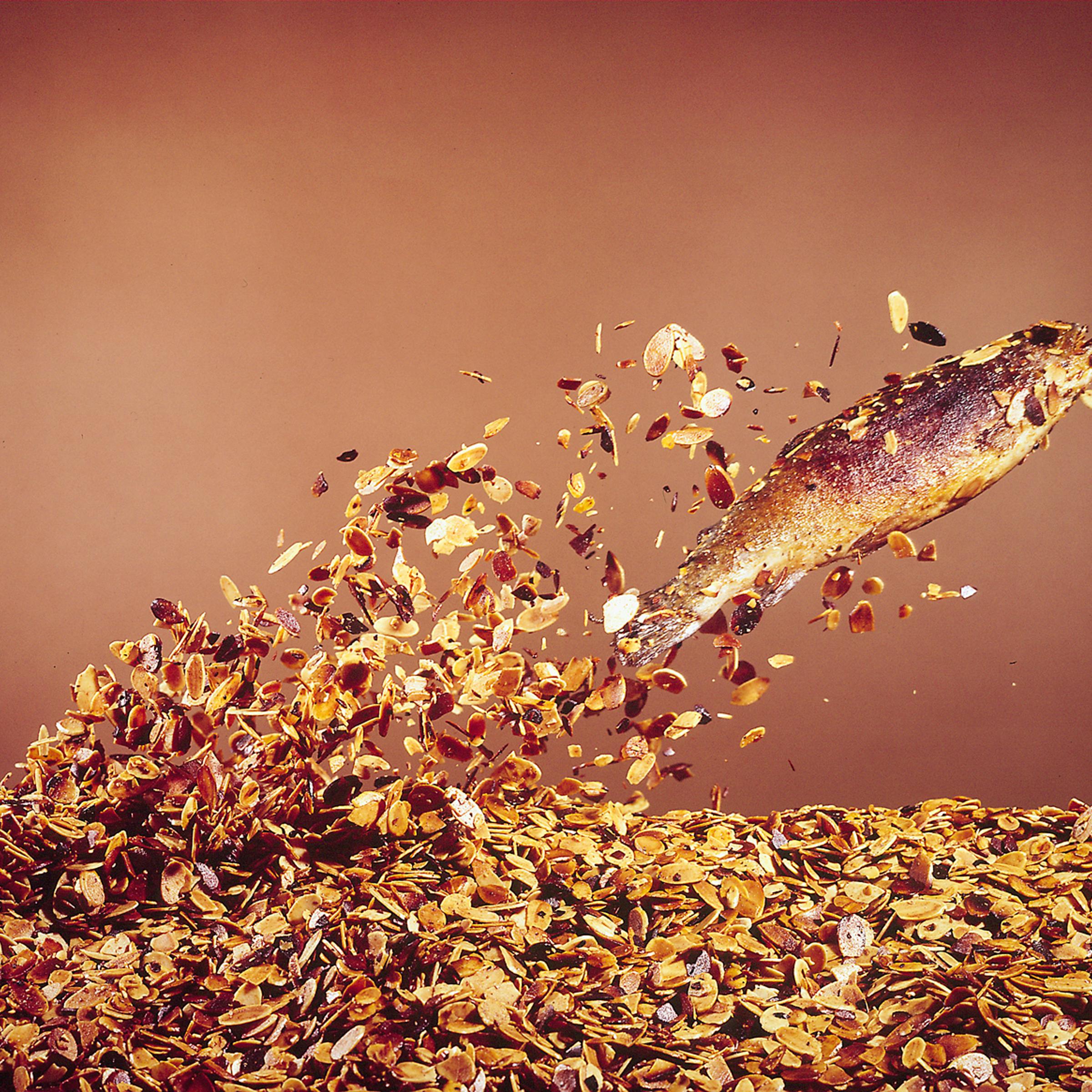 A hooked trout "flies" from a bed of almonds in preparation for Trout Amandine.