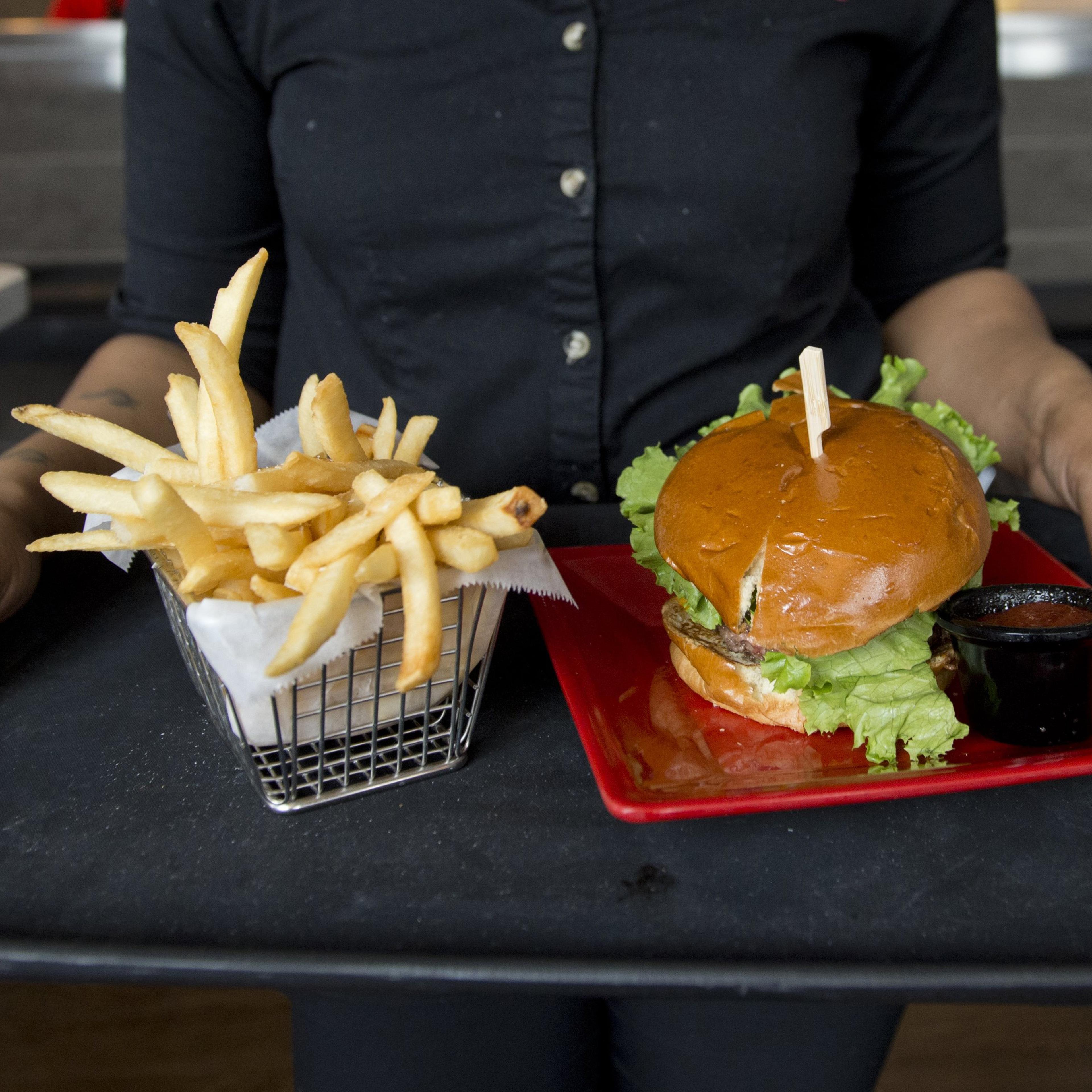 A server carries a tray with a hamburger and french fries at Bolt Burgers in Washington, DC on February 25, 2014.
