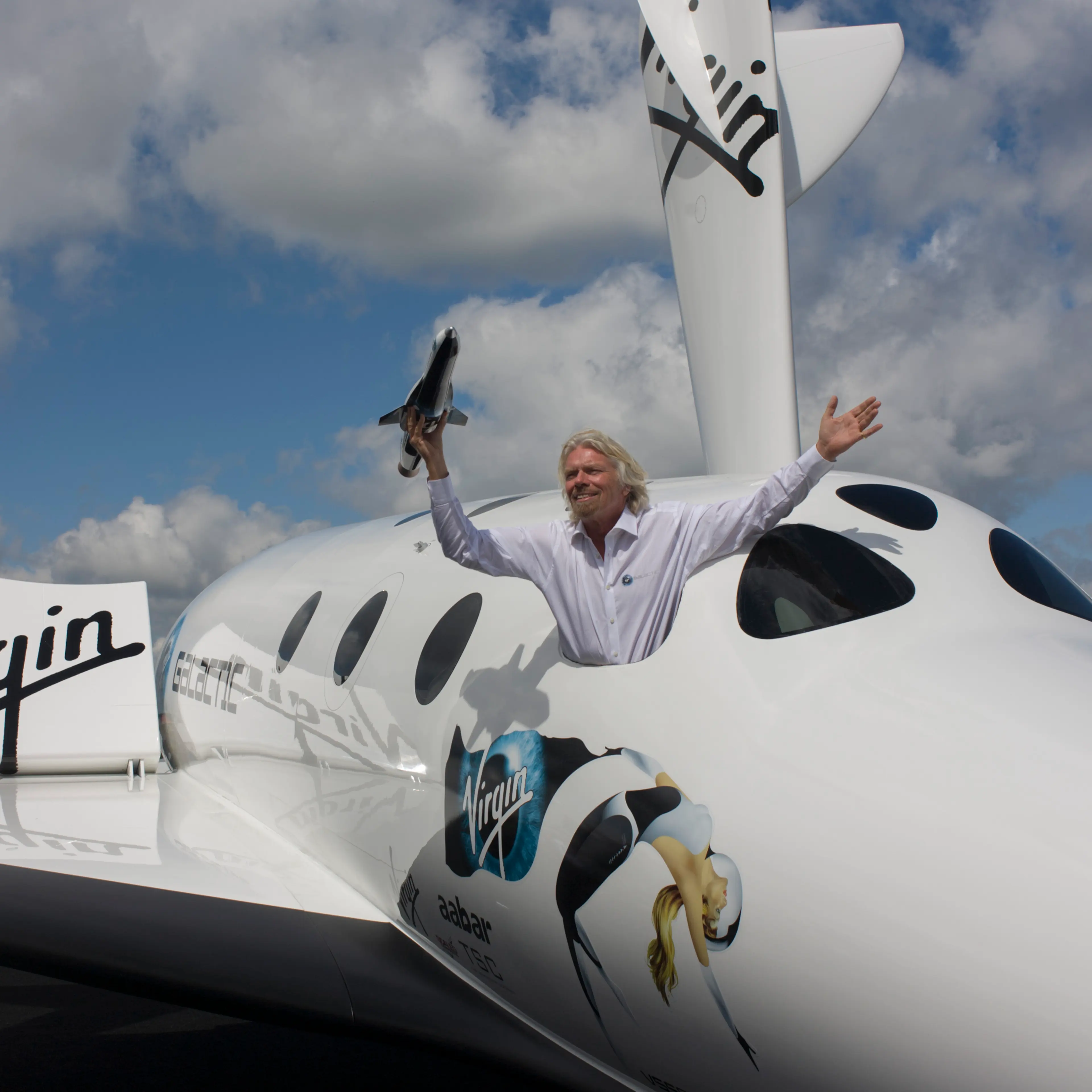 Alongside his SpaceShipTwo vehicle, Richard Branson holds model of satellite LauncherOne after Virgin Galactic space tourism presentation at the 2012 Farnborough Air Show.