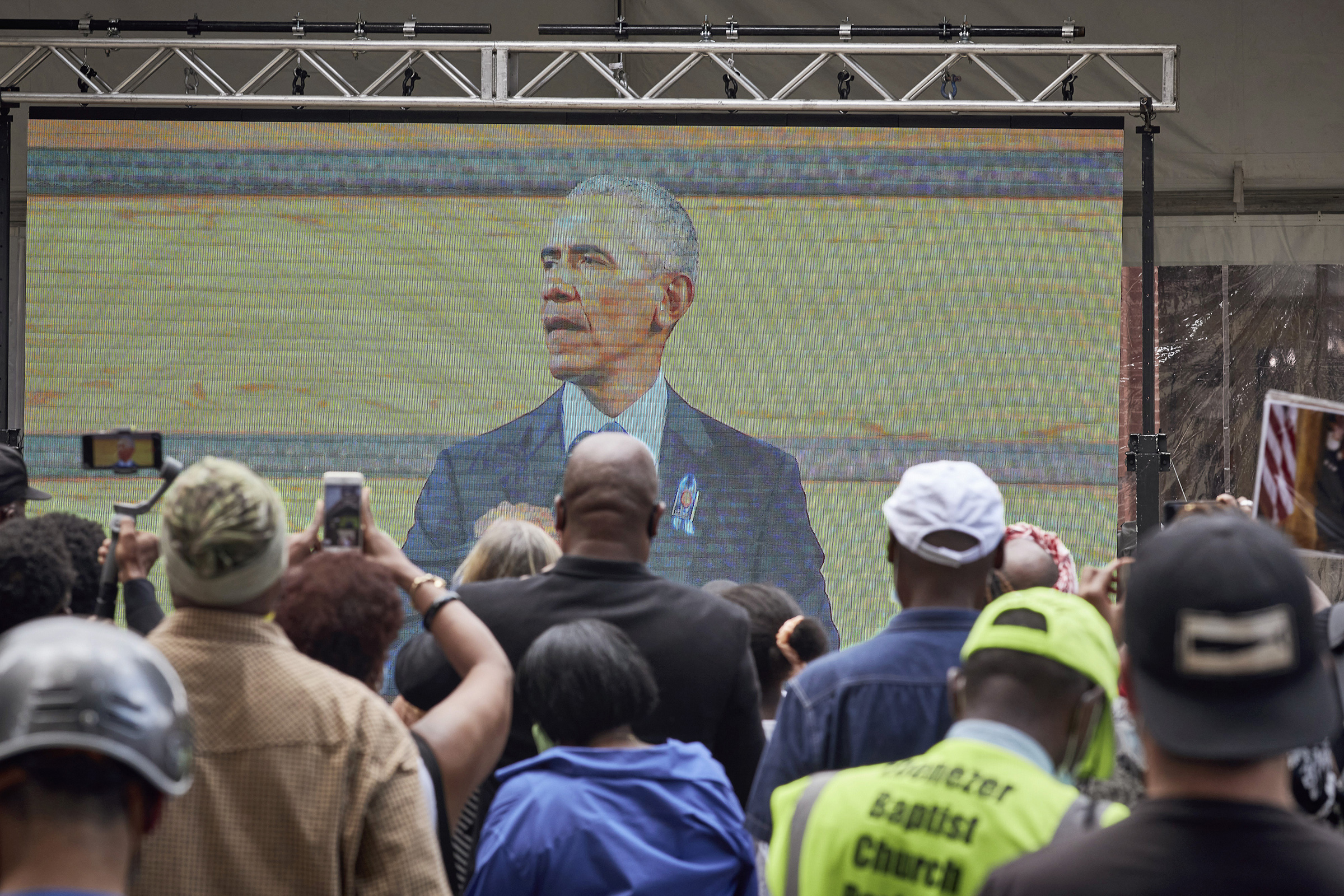Mourners watch a broadcast of former President Barack Obama speaking at the funeral for the late Rep. John Lewis (D-Ga.) outside Ebenezer Baptist Church, where Lewis' funeral is taking place, in Atlanta, July 30, 2020. (Melissa Golden/The New York Times)