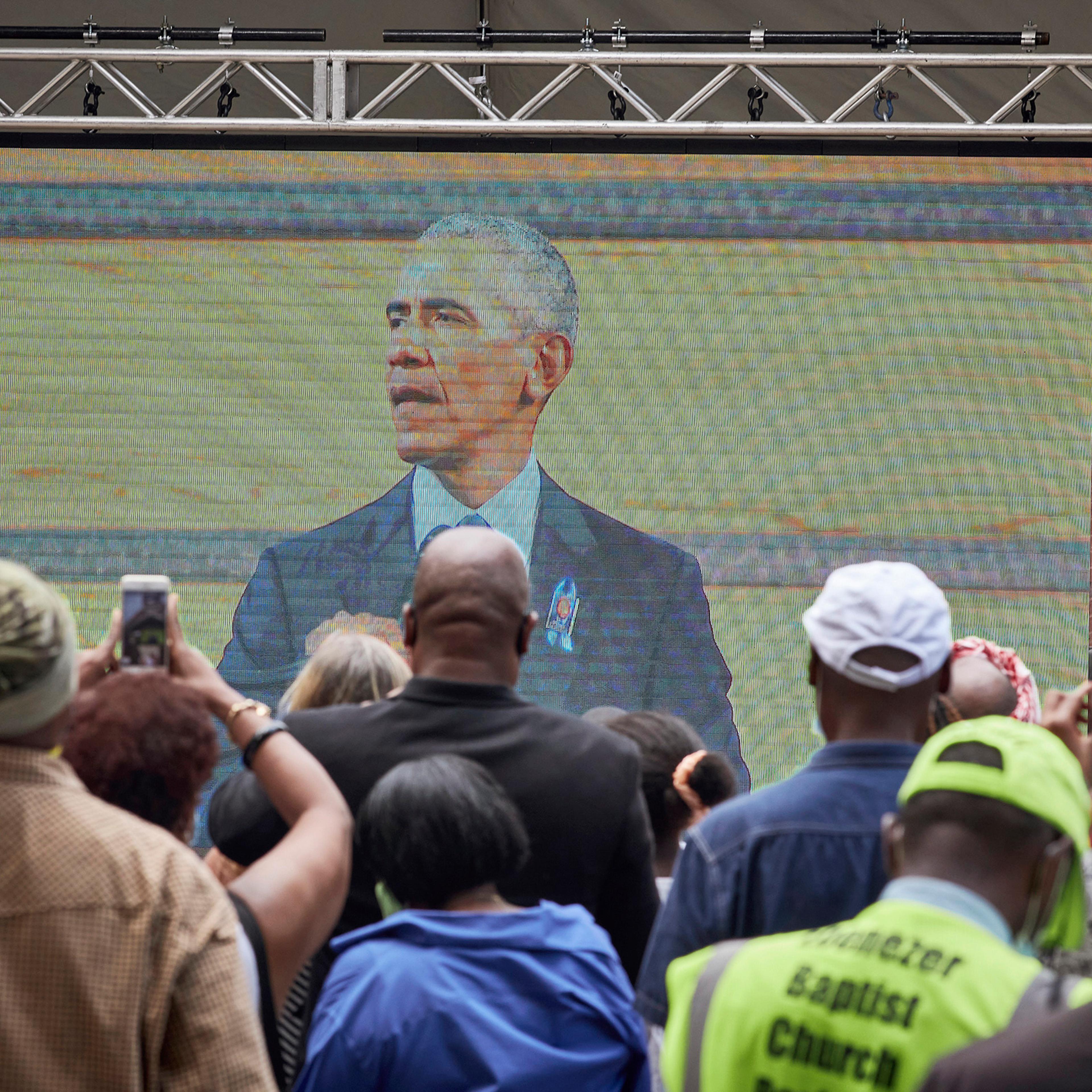Mourners watch a broadcast of former President Barack Obama speaking at the funeral for the late Rep. John Lewis (D-Ga.) outside Ebenezer Baptist Church, where Lewis' funeral is taking place, in Atlanta, July 30, 2020. (Melissa Golden/The New York Times)