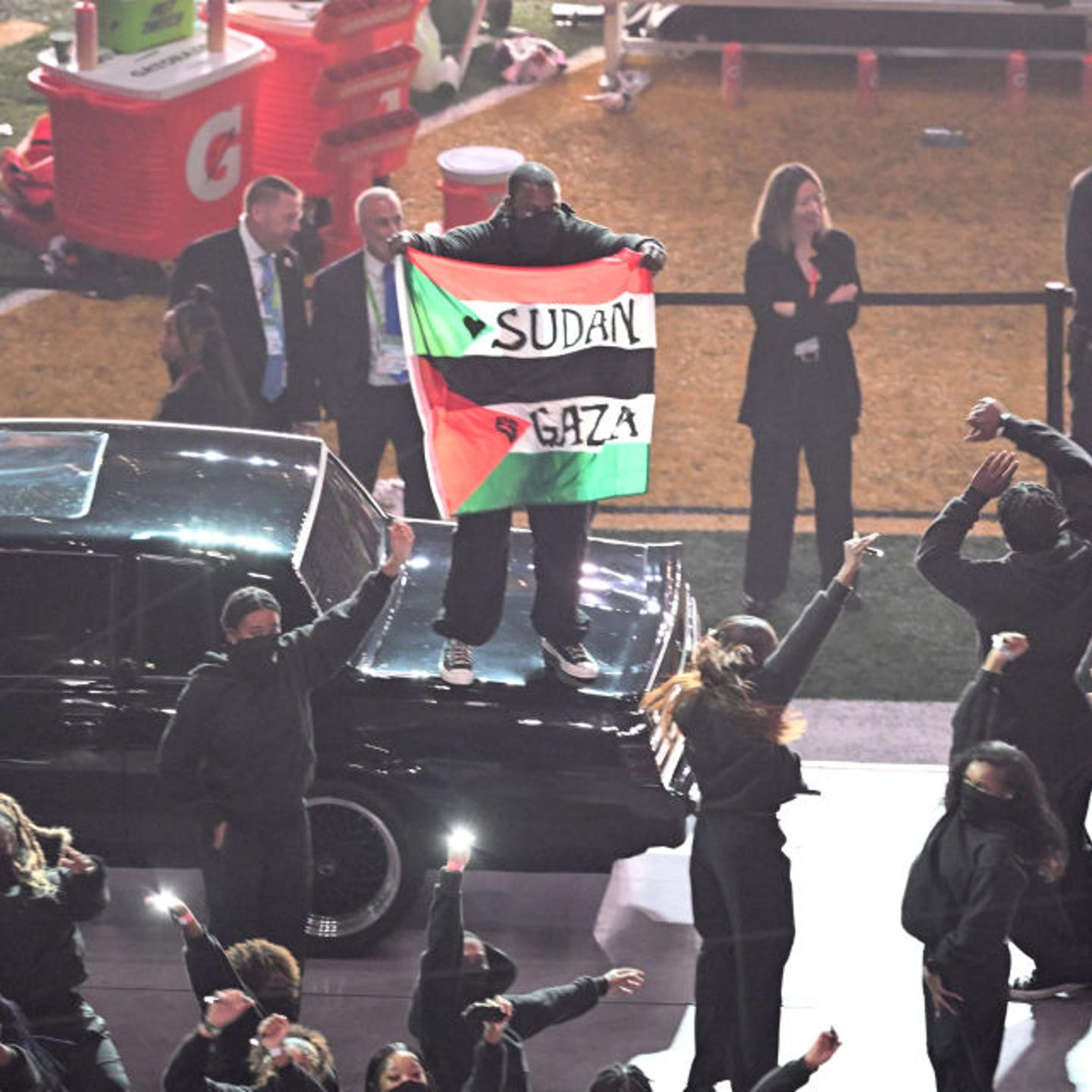 A protestor holds a Palestinian flag with the words "Gaza" and "Sudan" as rapper Kendrick Lamar performs during Super Bowl LIX Chiefs vs Eagles Apple Music Halftime Show at Caesars Superdome in New Orleans, Louisiana, on Feb. 9, 2025.