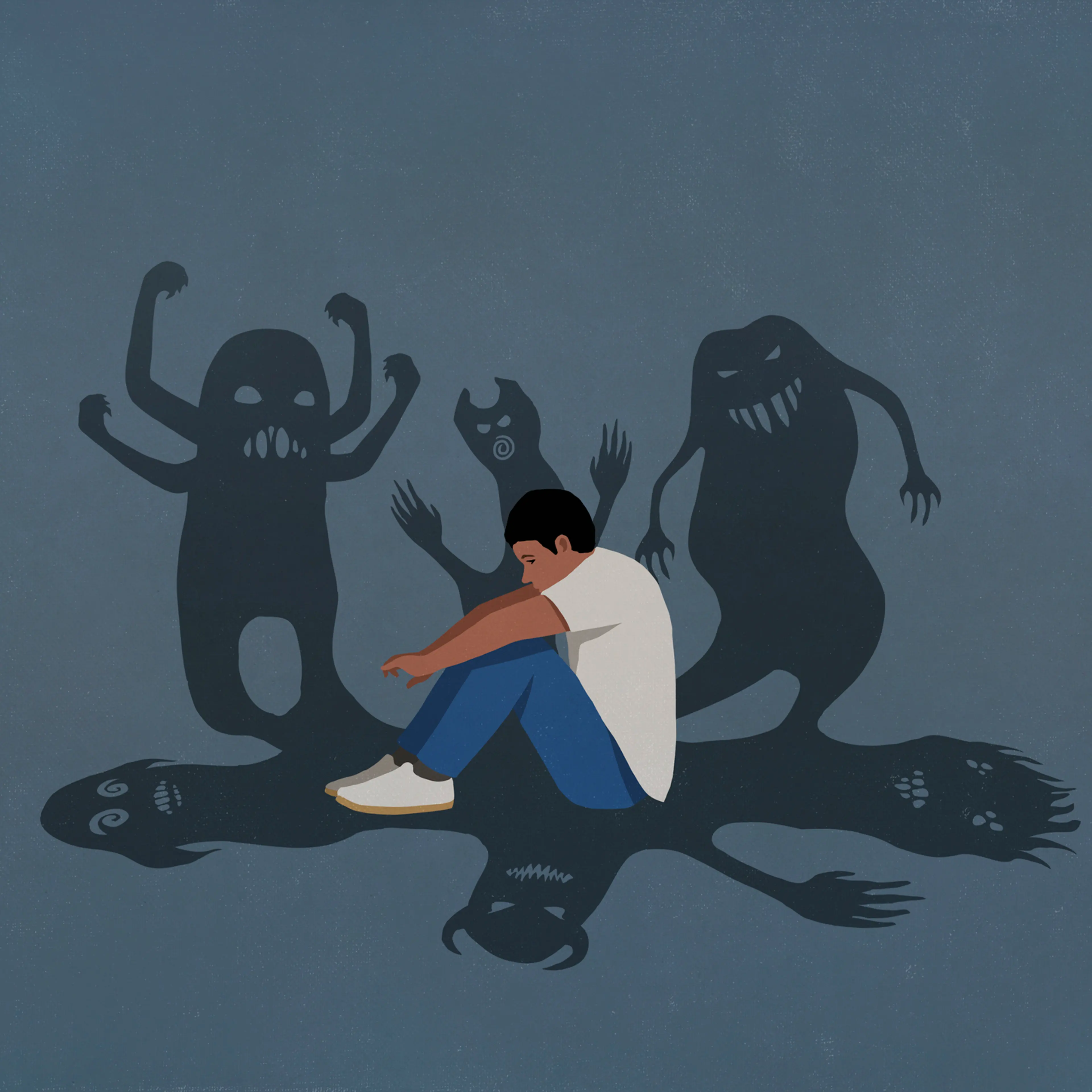 Shadows of monsters surrounding anxious teenage boy hugging knees