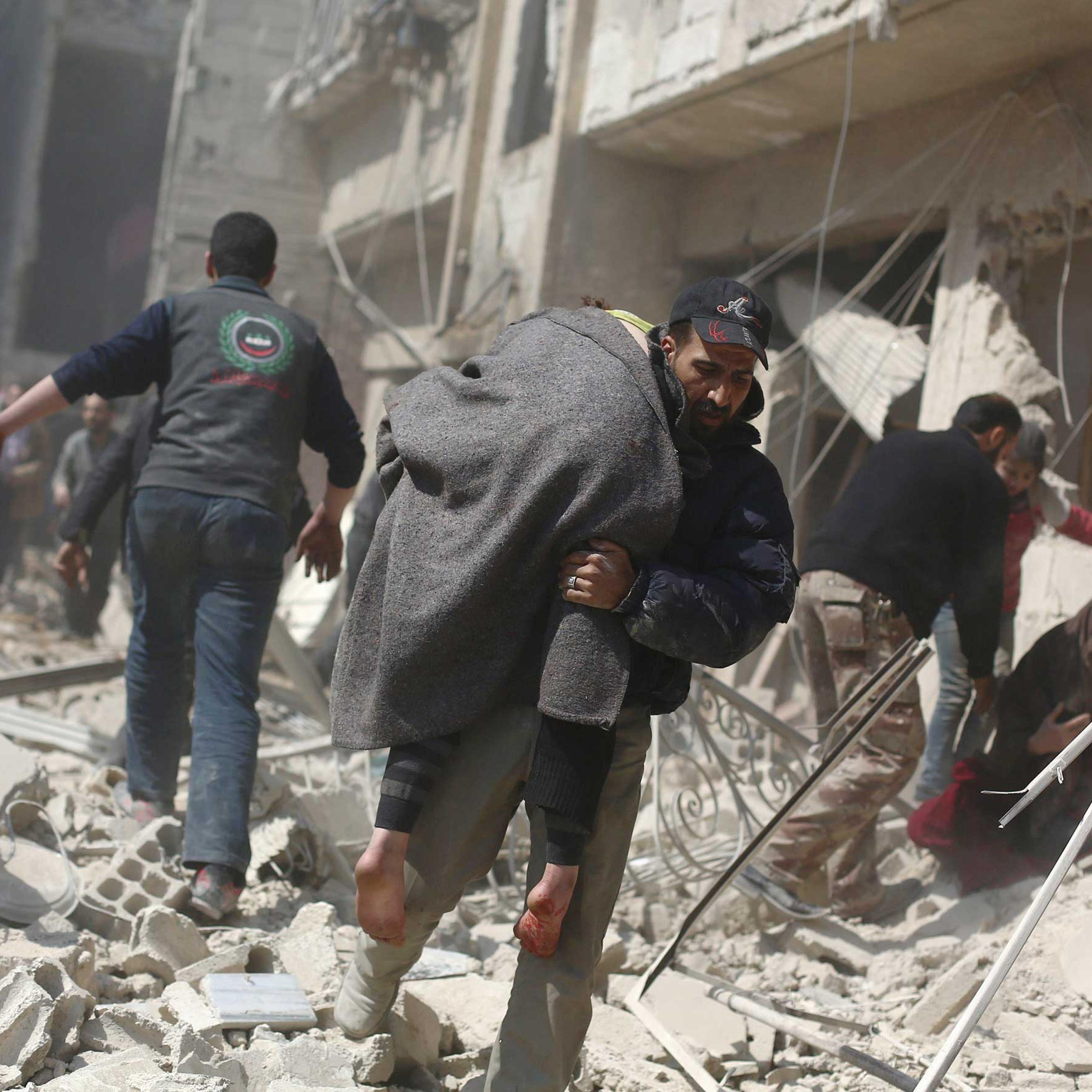 A man carries a wounded person in the rebel-held area of Douma, east of the Syrian capital Damascus, following reported air strikes by regime forces on March 15, 2015.