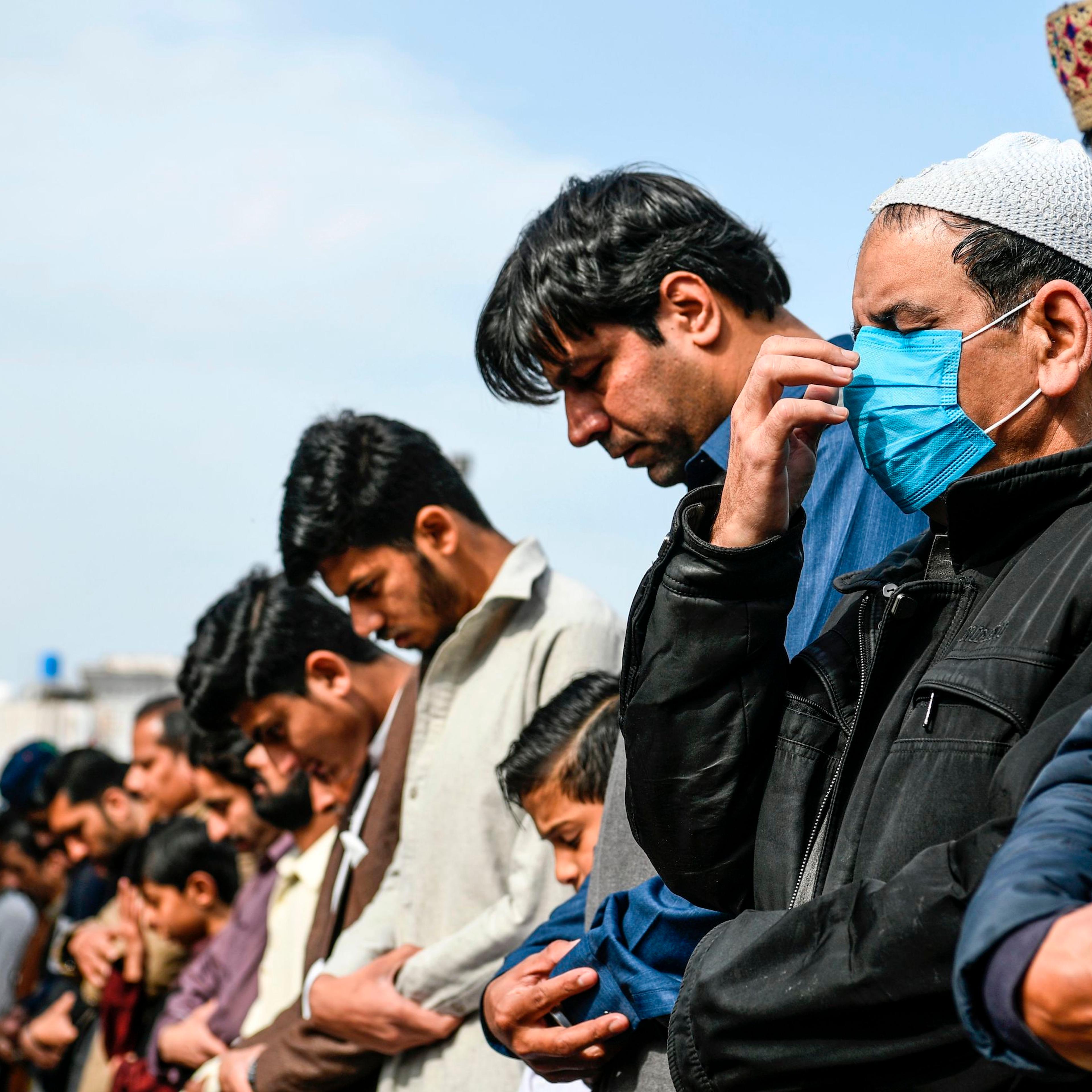 A resident (R) wearing a facemask as a preventive measure against the spread of the COVID-19 coronavirus offers Friday prayers along with other Muslims at a mosque in Rawalpindi on March 13, 2020.