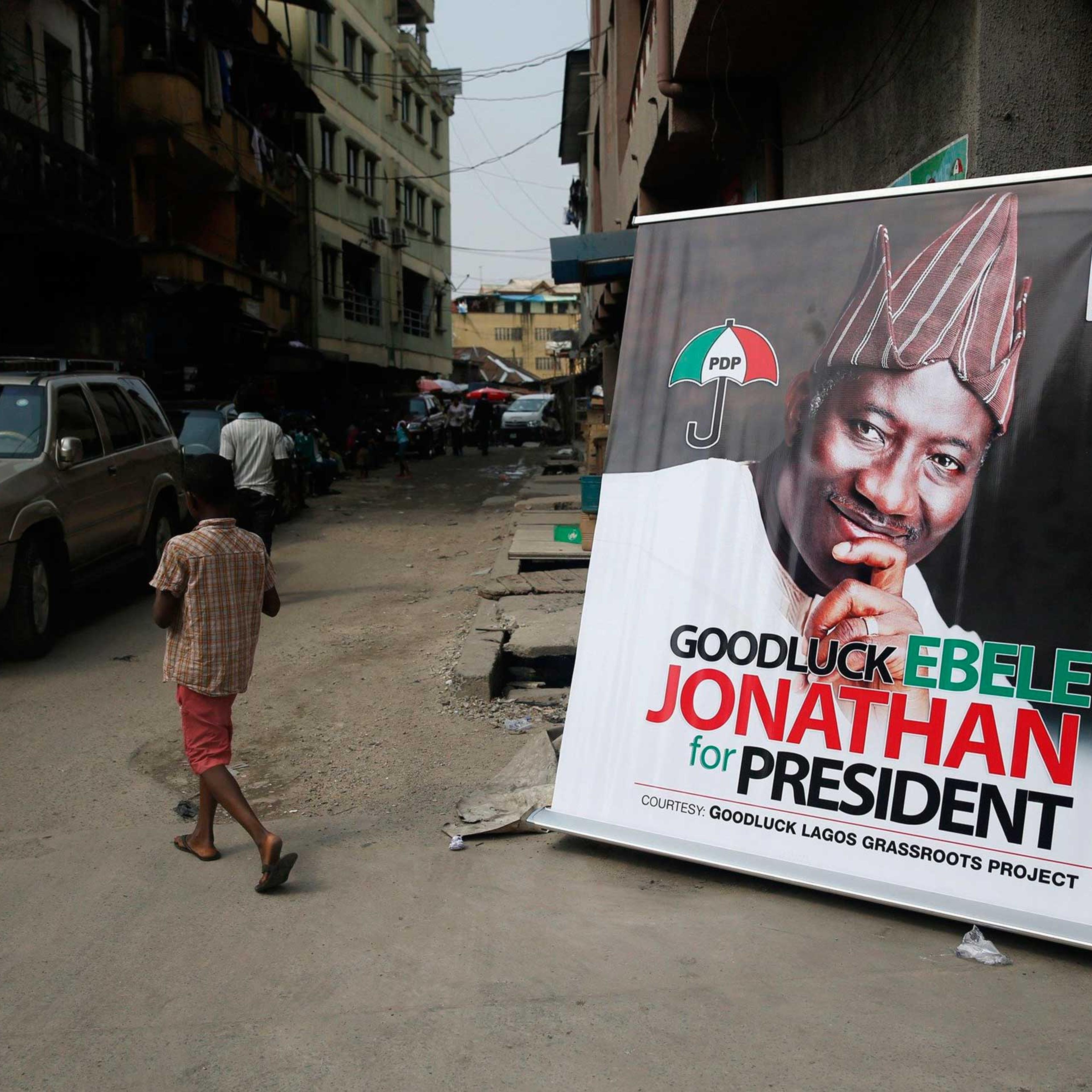 A boy walks near a banner campaigning for Nigeria's President Goodluck Jonathan along a street at Campus Square neighborhood in Lagos, Feb. 2, 2015.