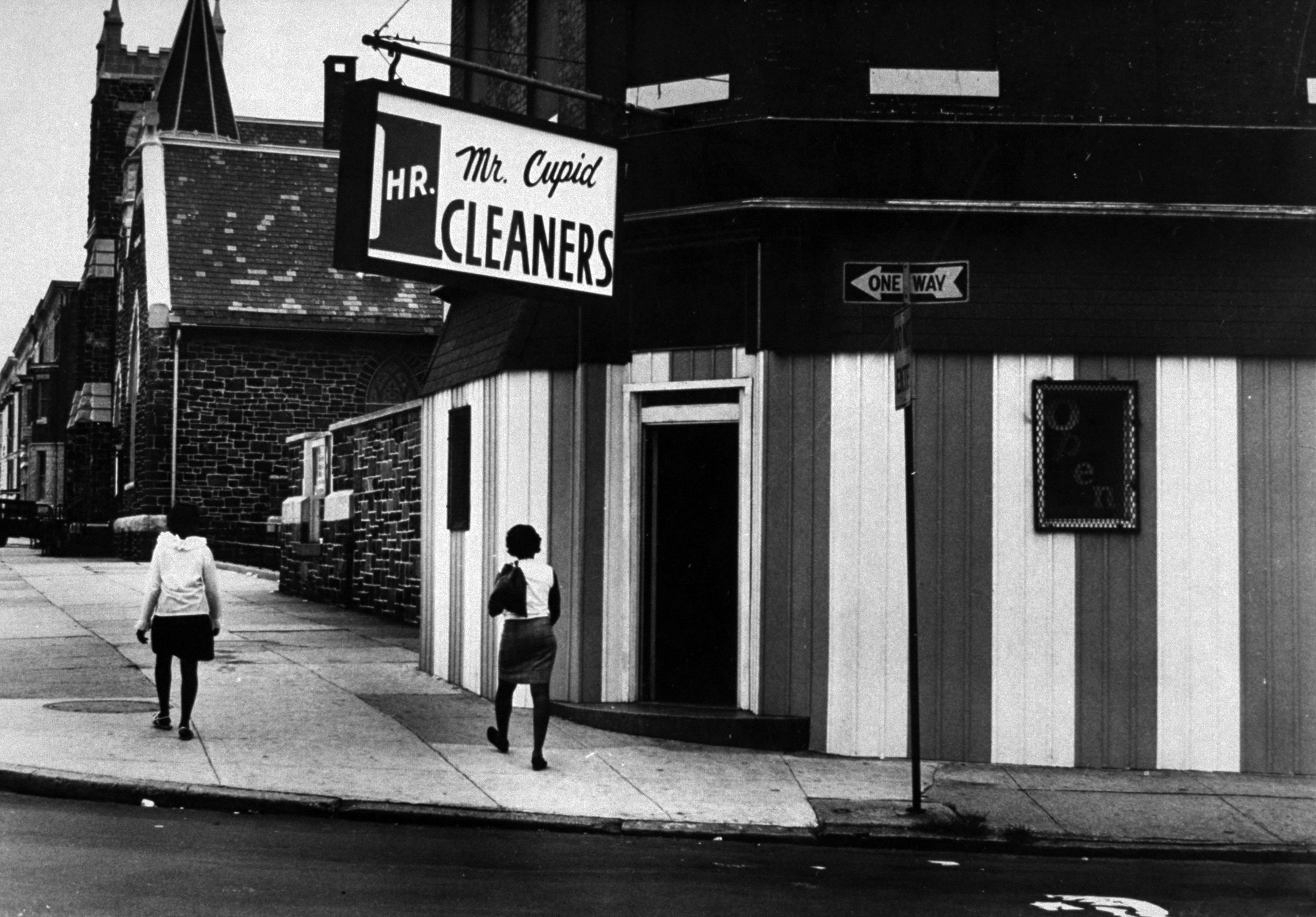 To safeguard against break-ins and looting, many merchants have adopted the newest style in urban architecture—"Riot Renaissance." Window displays are eliminated, and so are the windows. At a dry-cleaning shop, striped sheets of plywood now cover the fac