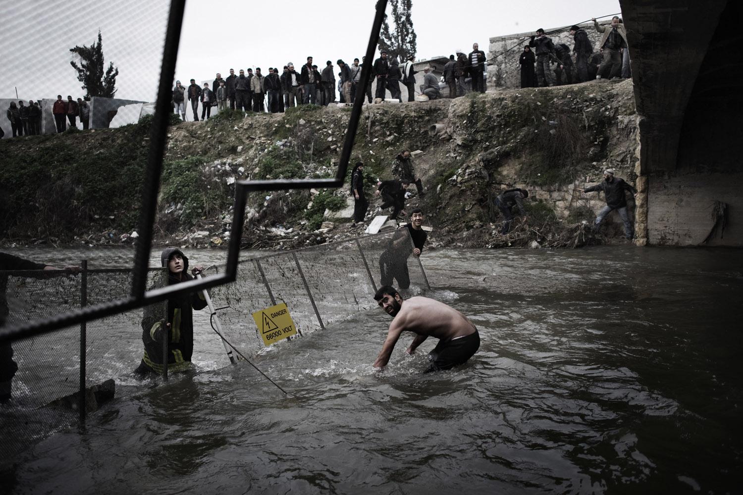 The day after victims of the massacre were first discovered, officials moved fencing into the river to help catch additional bodies as they floated downstream near Aleppo, Jan. 30, 2013.