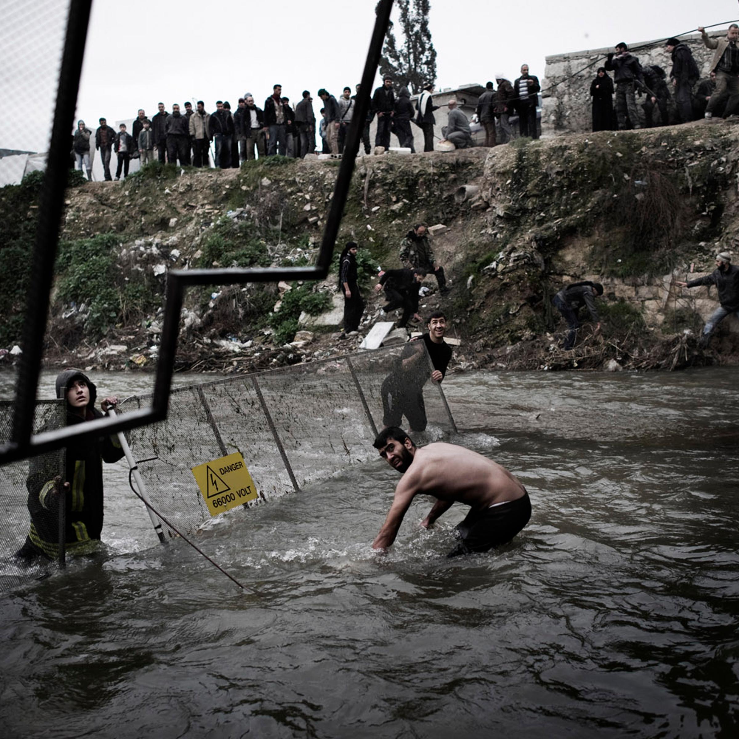The day after victims of the massacre were first discovered, officials moved fencing into the river to help catch additional bodies as they floated downstream near Aleppo, Jan. 30, 2013.