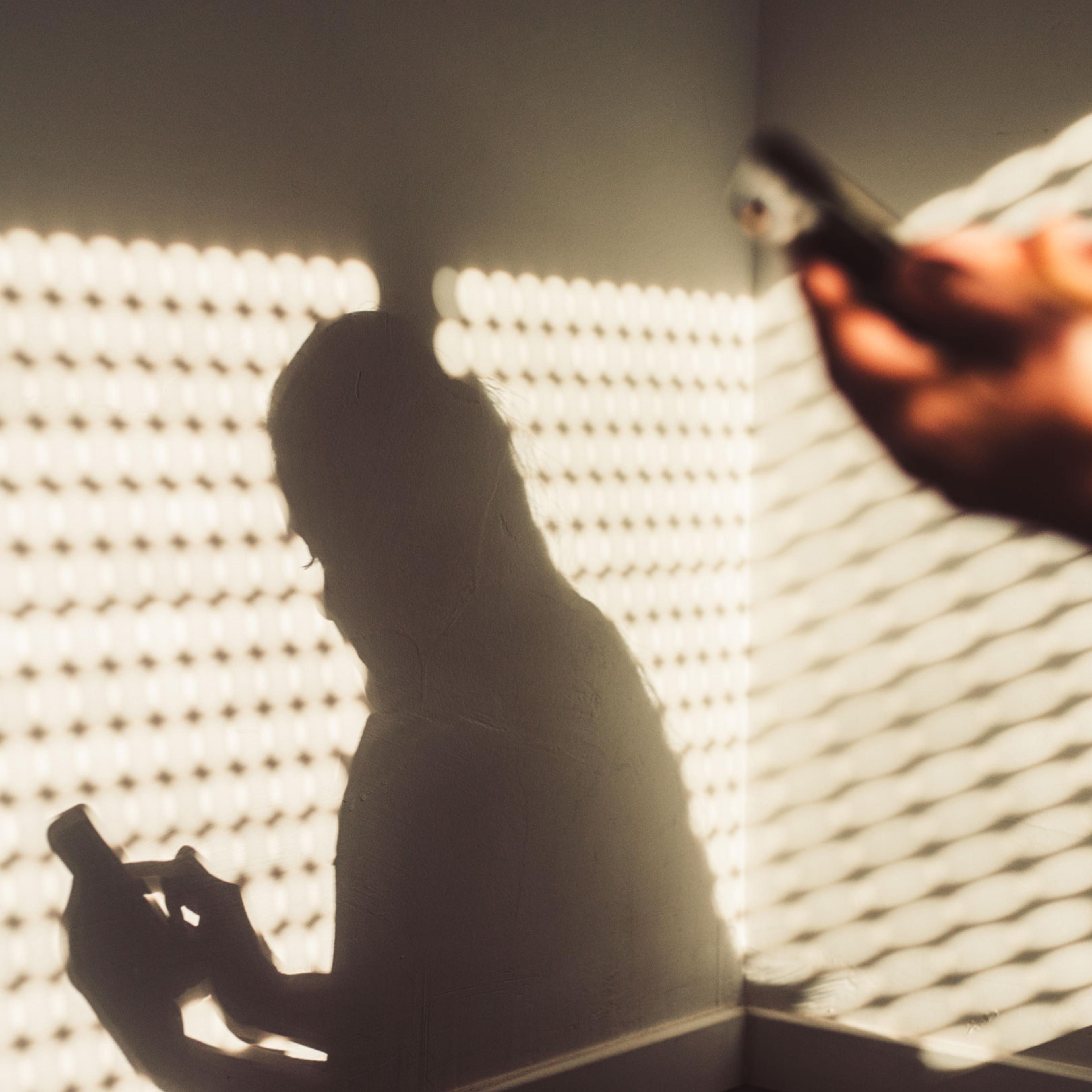 Shadow of a woman using a smartphone