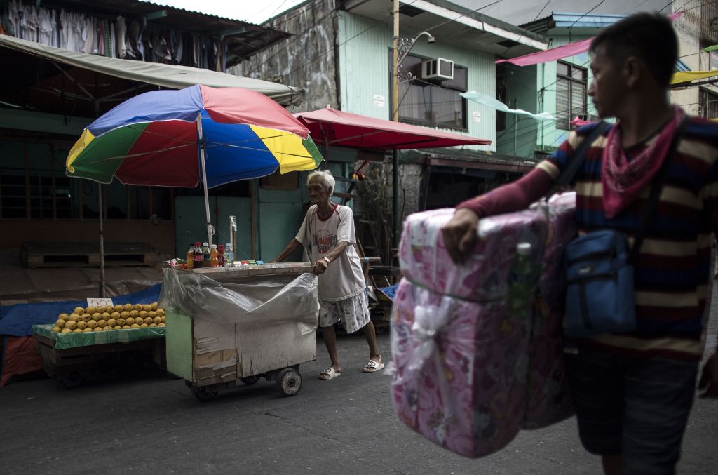 This photo taken on June 2, 2018 shows street vendor and Golden Gays member Al Enriquez, 82, also known as "Carmen Dela Rue", posing for a photograph by his wooden cart on a street in Manila.