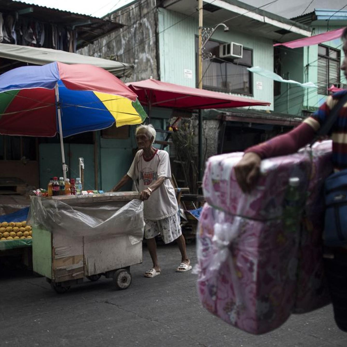 This photo taken on June 2, 2018 shows street vendor and Golden Gays member Al Enriquez, 82, also known as "Carmen Dela Rue", posing for a photograph by his wooden cart on a street in Manila.