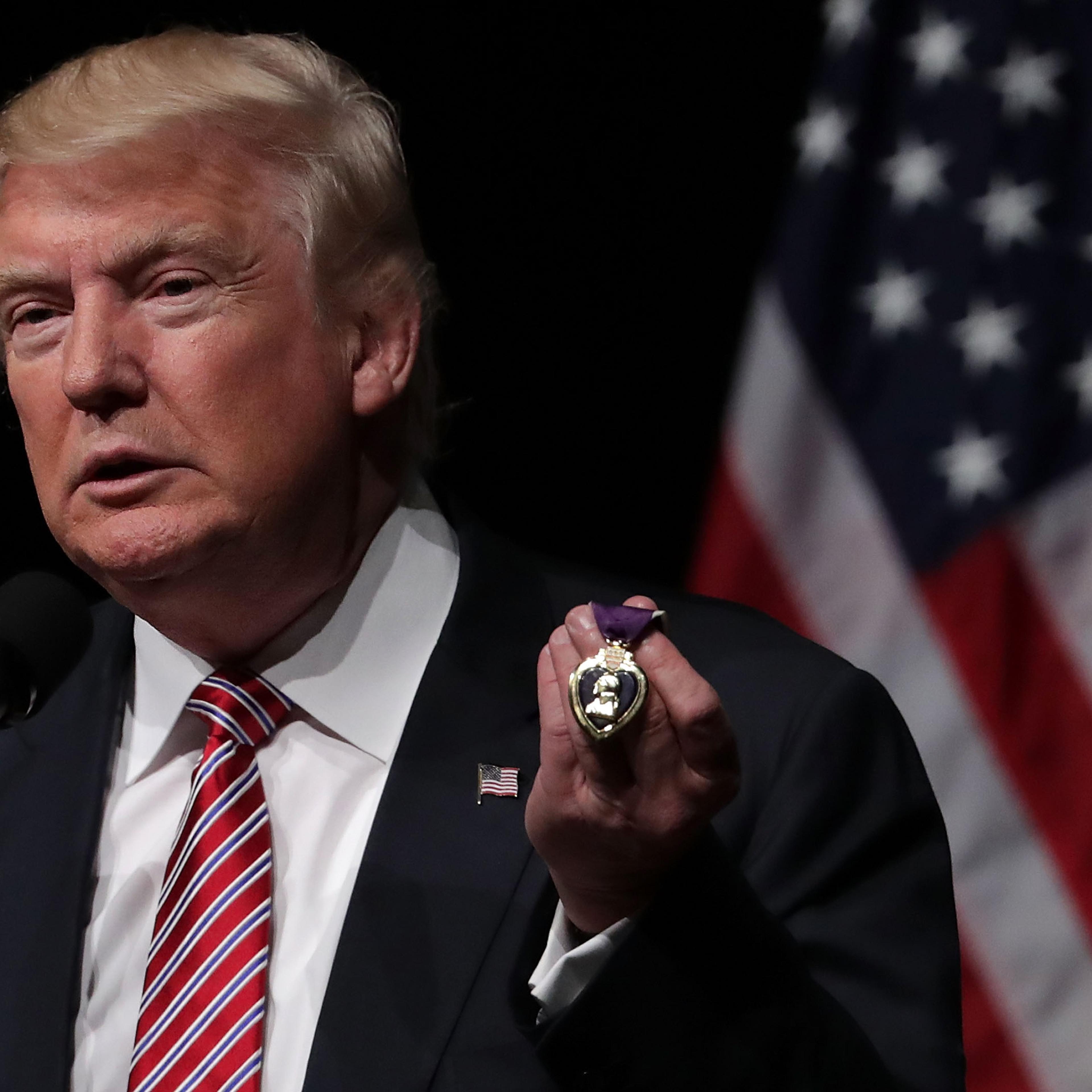 Republican presidential nominee Donald Trump holds a Purple Heart, given to him by veteran Louis Dorfman, during a campaign event at Briar Woods High School in Ashburn, Va., on Aug. 2, 2016.