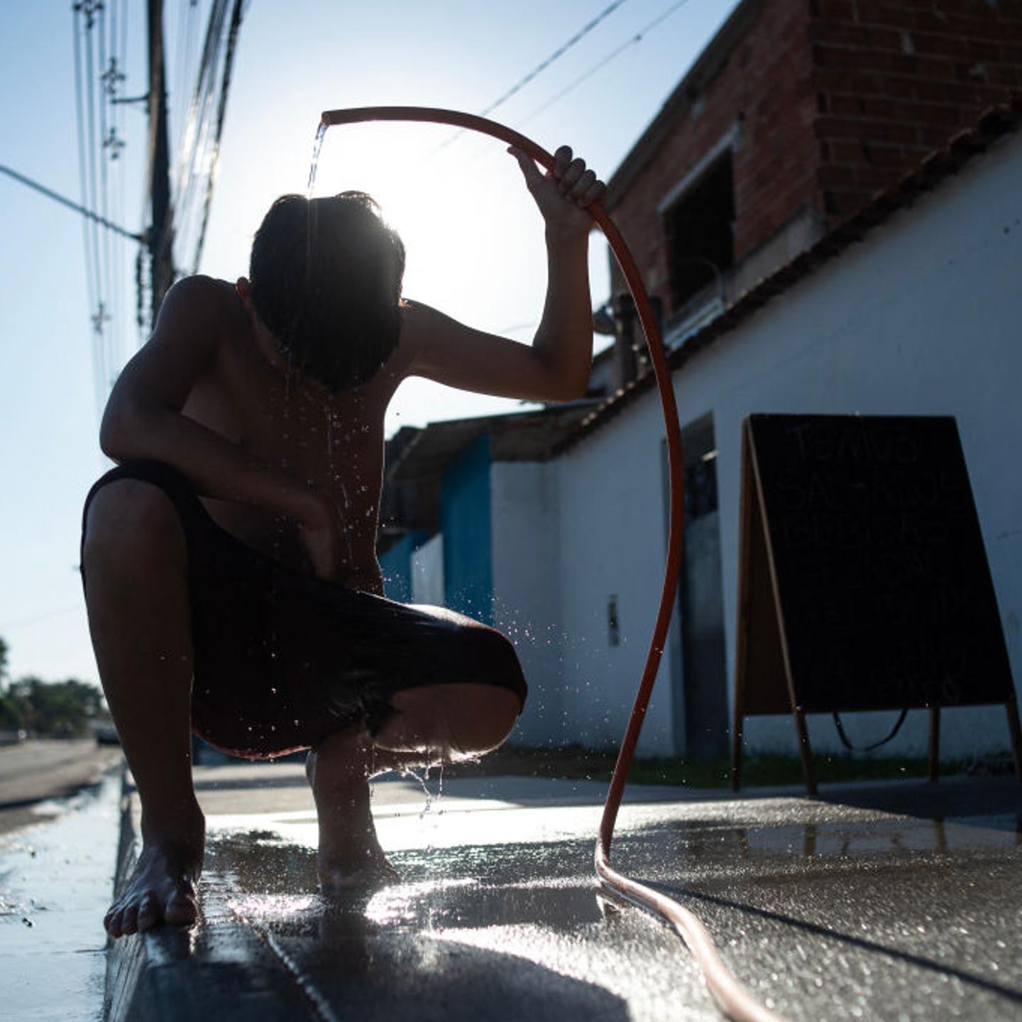 A boy cools off with a hose on the street amid a heat wave in the Guaratiba neighborhood of Rio de Janeiro, Brazil, on Feb. 17, 2025.