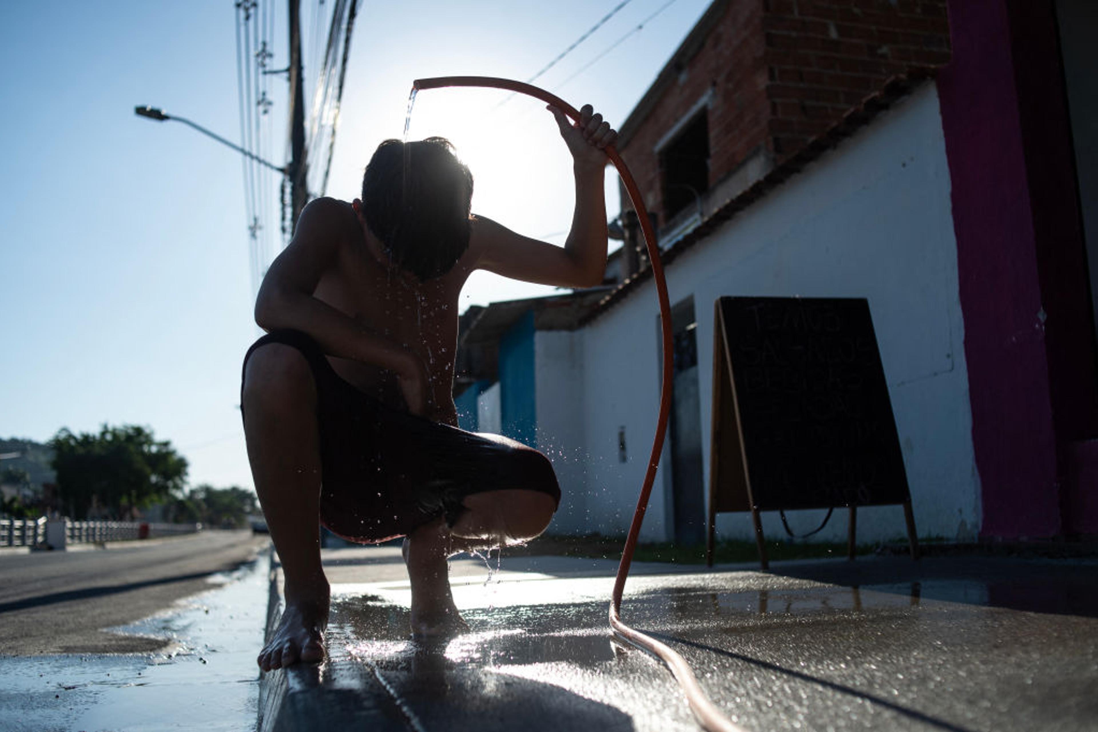 A boy cools off with a hose on the street amid a heat wave in the Guaratiba neighborhood of Rio de Janeiro, Brazil, on Feb. 17, 2025.