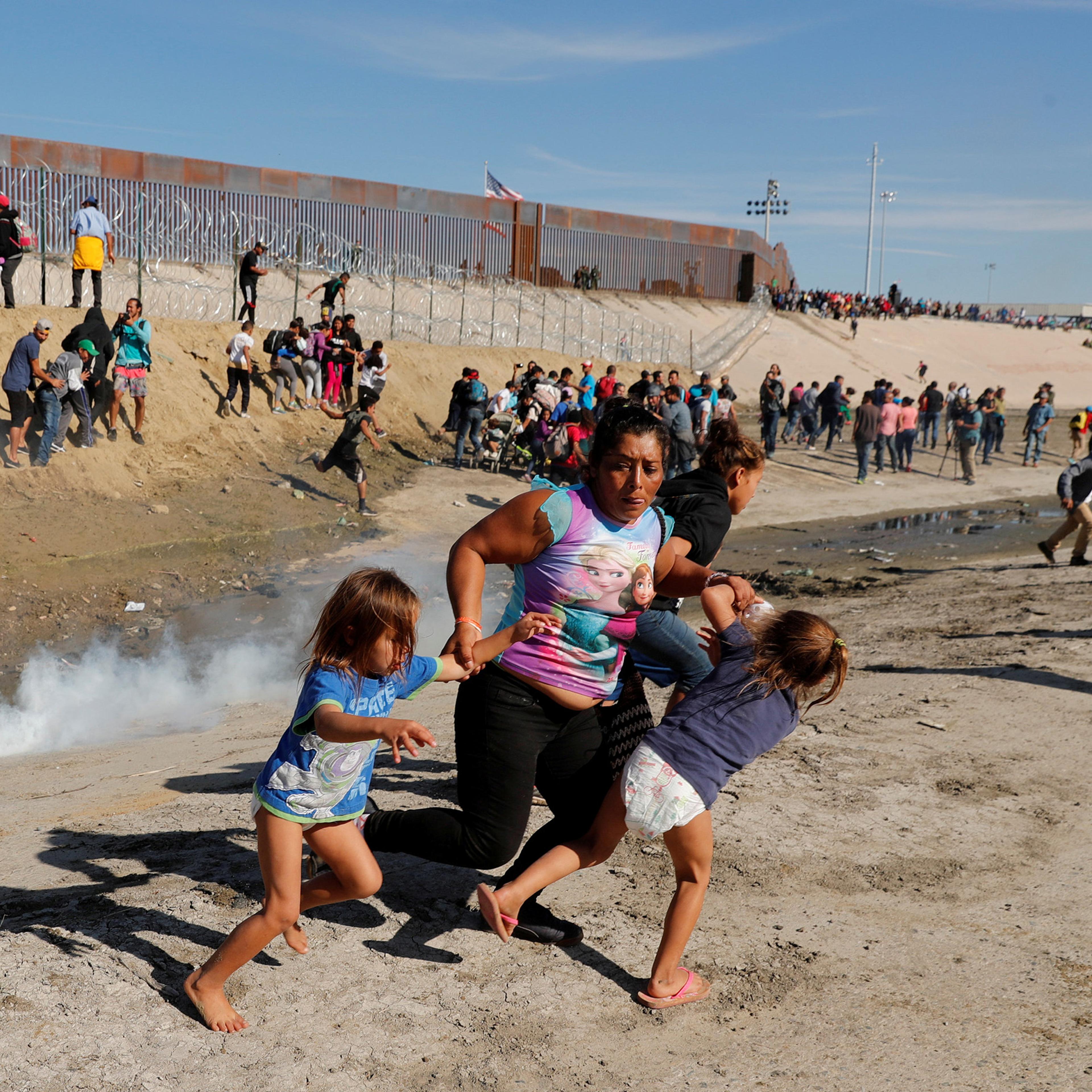 A migrant family, part of a caravan of thousands traveling from Central America to the United States, run away from tear gas