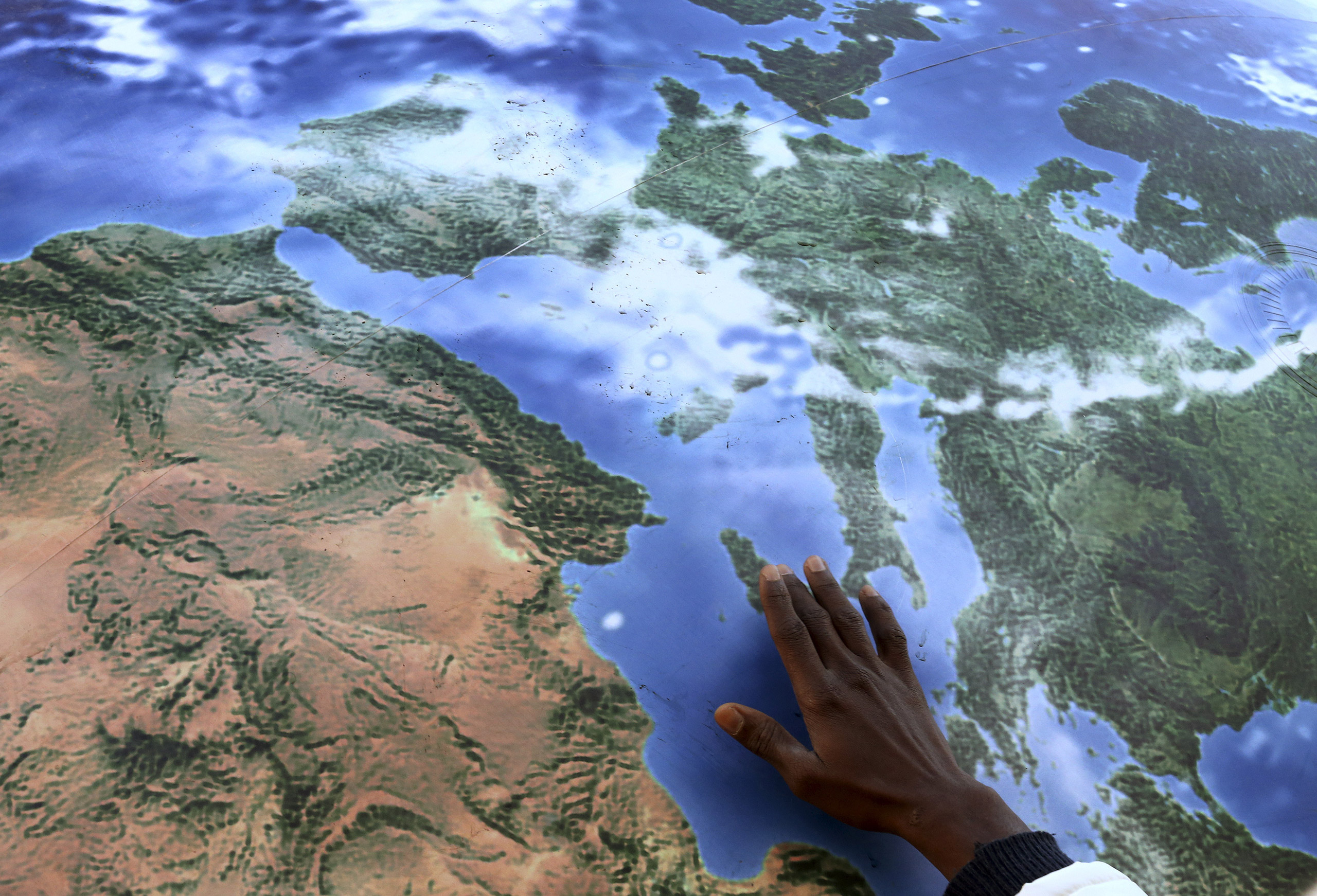 A migrant touches a globe shaped balloon during a rally held ahead of the start of the 2015 Paris World Climate Change Conference, known as the COP21 summit, in Rome, Italy , November 29, 2015. REUTERS/Alessandro Bianchi - RTX1WCFA