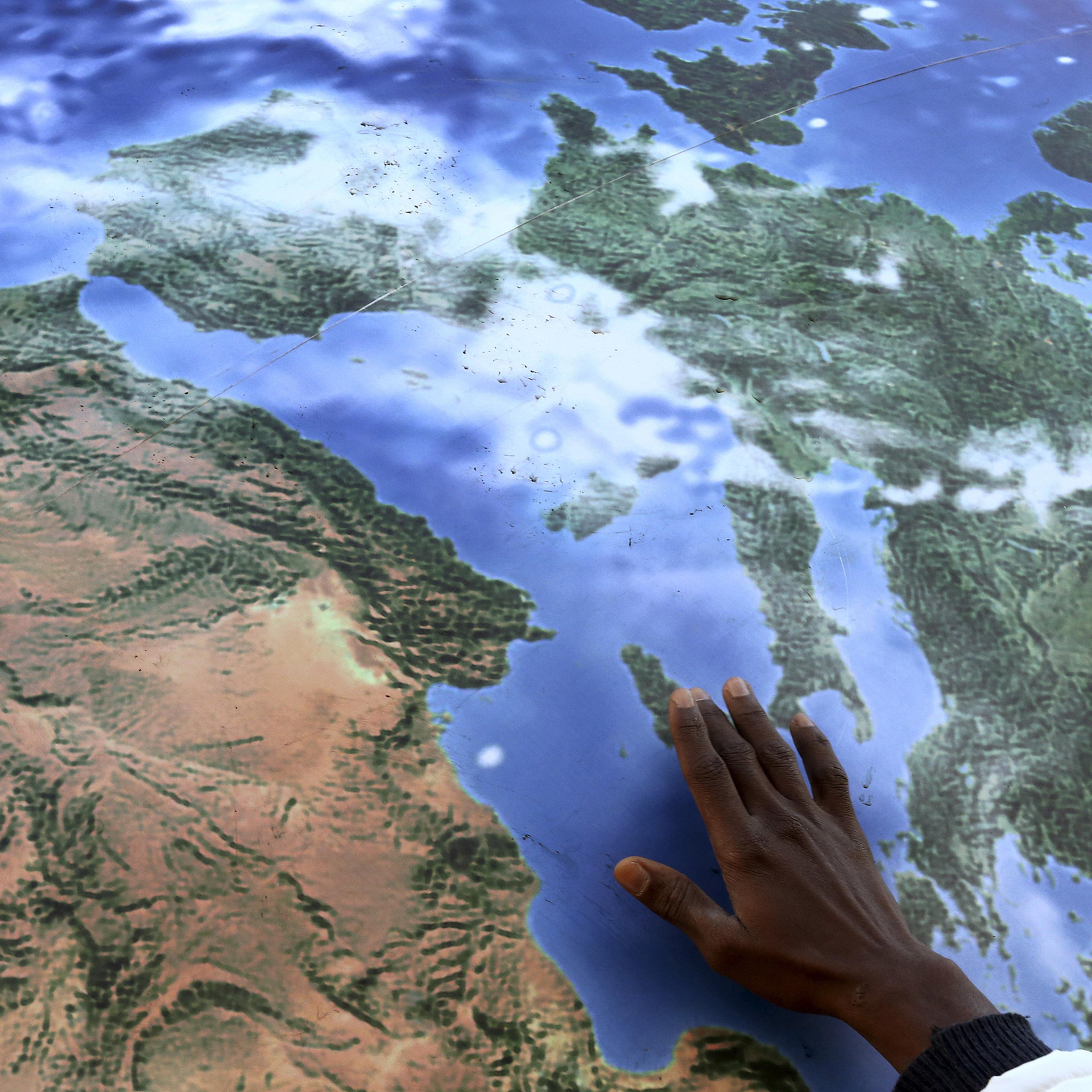 A migrant touches a globe shaped balloon during a rally held ahead of the start of the 2015 Paris World Climate Change Conference, known as the COP21 summit, in Rome, Italy , November 29, 2015. REUTERS/Alessandro Bianchi - RTX1WCFA