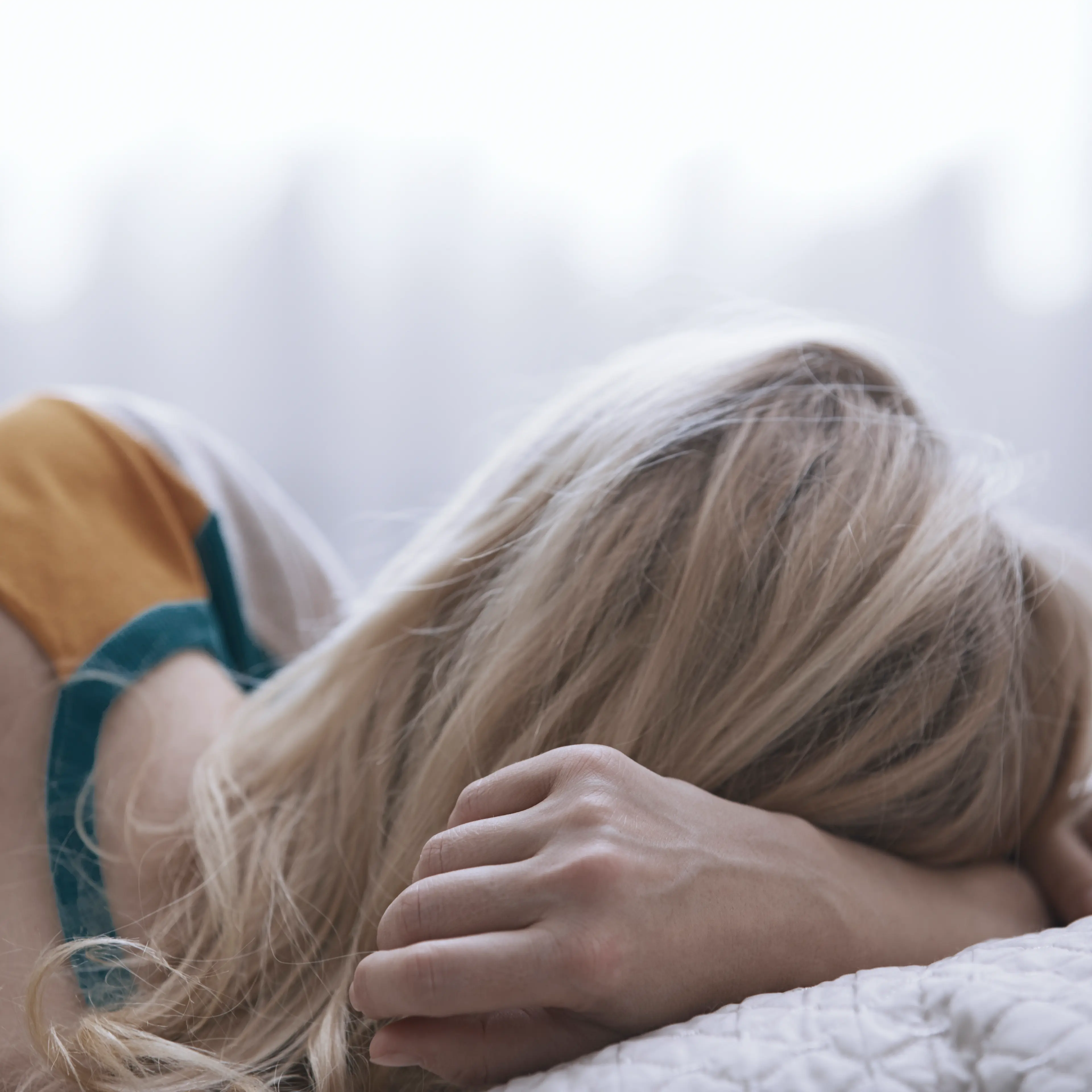 Blonde woman laying on bed TIME health stock