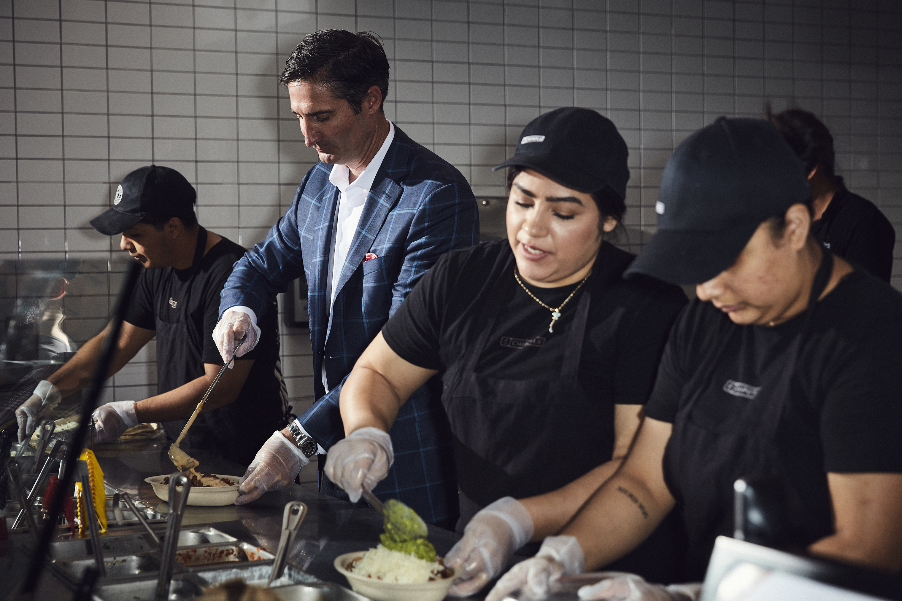 Chipotle CEO Brian Niccol, who started the job in March, works behind the counter with Chipotle employees at a location in Newport Beach, Calif. 
