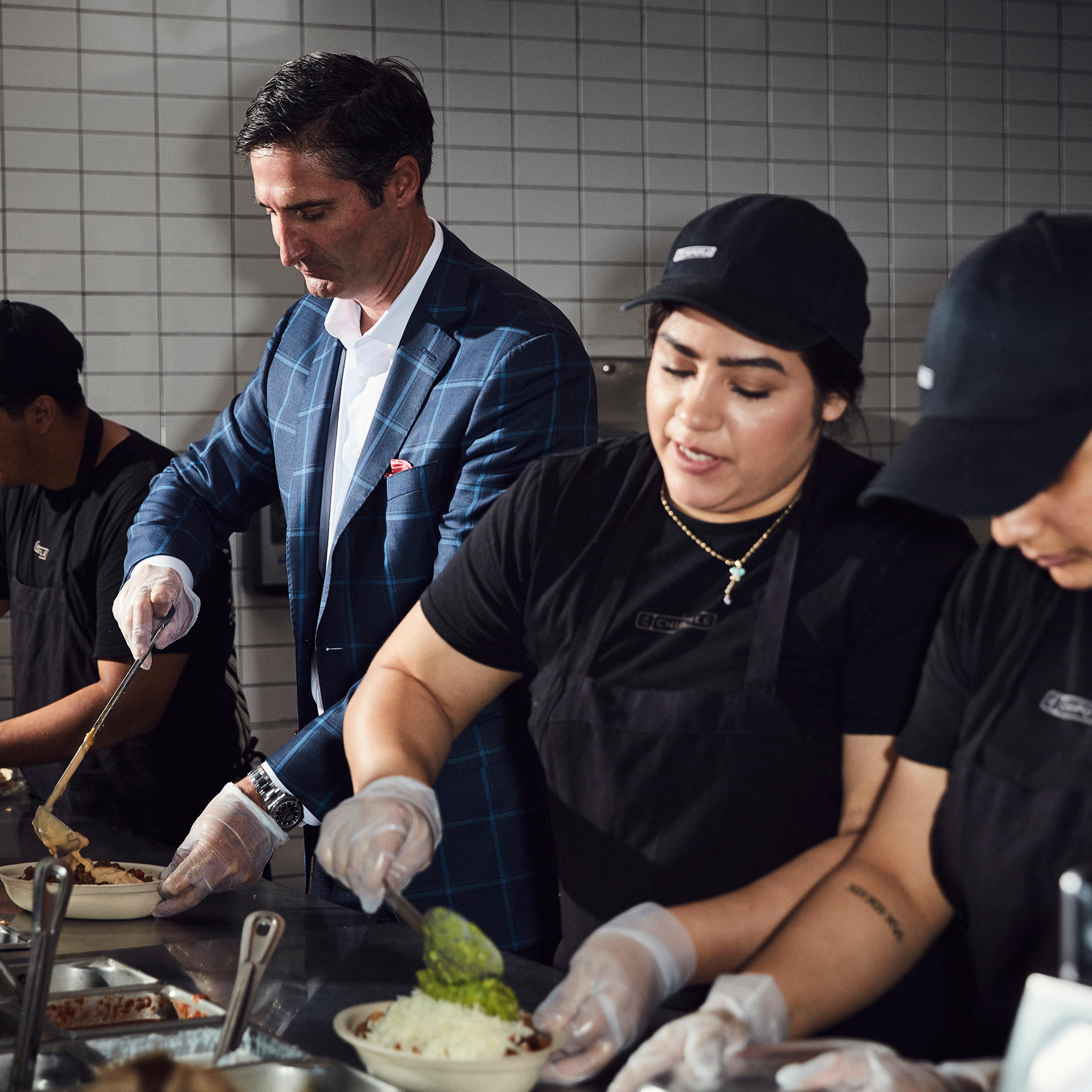 Chipotle CEO Brian Niccol, who started the job in March, works behind the counter with Chipotle employees at a location in Newport Beach, Calif.