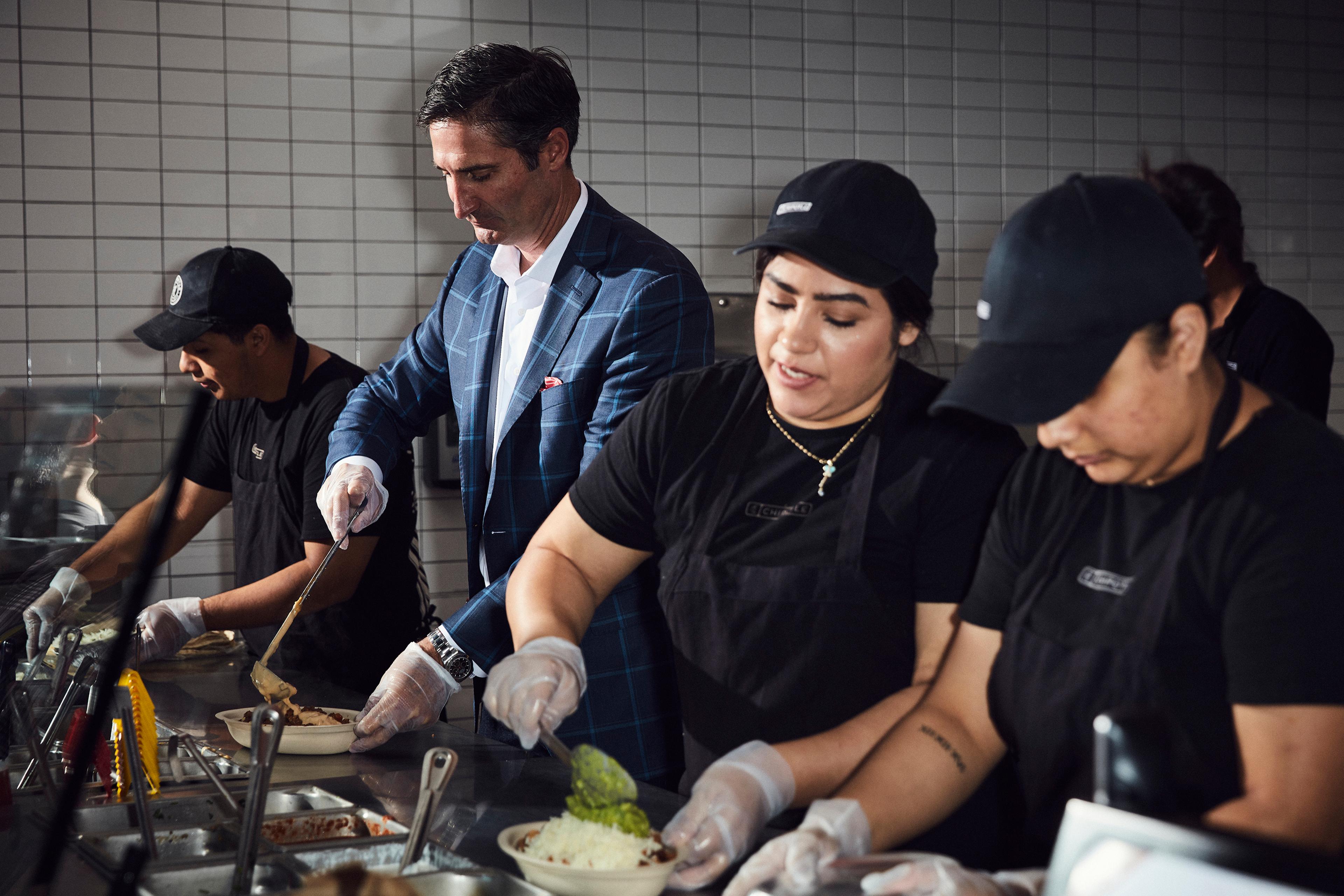 Chipotle CEO Brian Niccol, who started the job in March, works behind the counter with Chipotle employees at a location in Newport Beach, Calif.