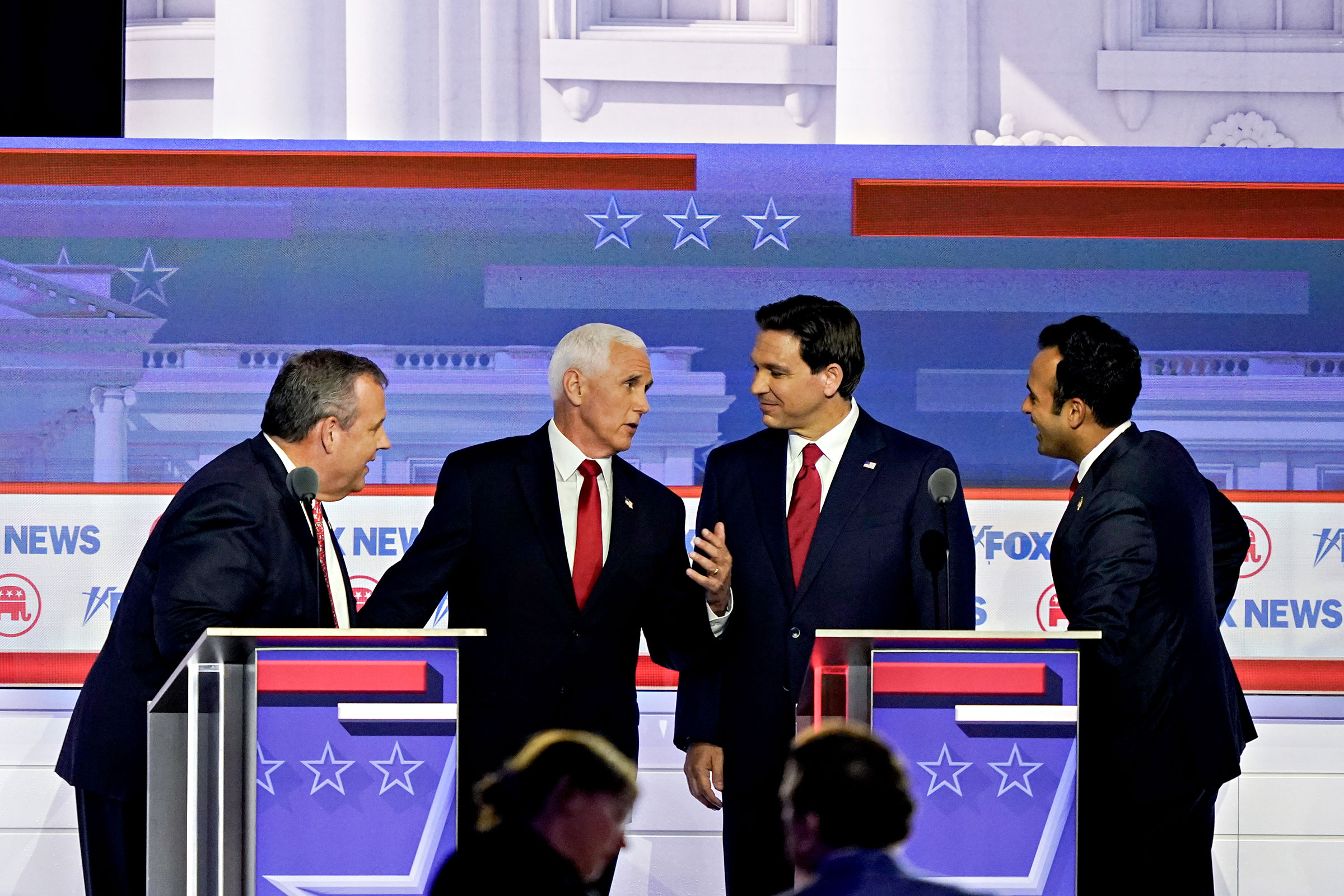 Former governor of N.J. Chris Christie, former Vice President Mike Pence, Fla. Gov. Ron DeSantis, and Vivek Ramaswamy speak to each other away from their podiums during a break at the Republican primary presidential debate in Milwaukee, on Aug. 23, 2023.