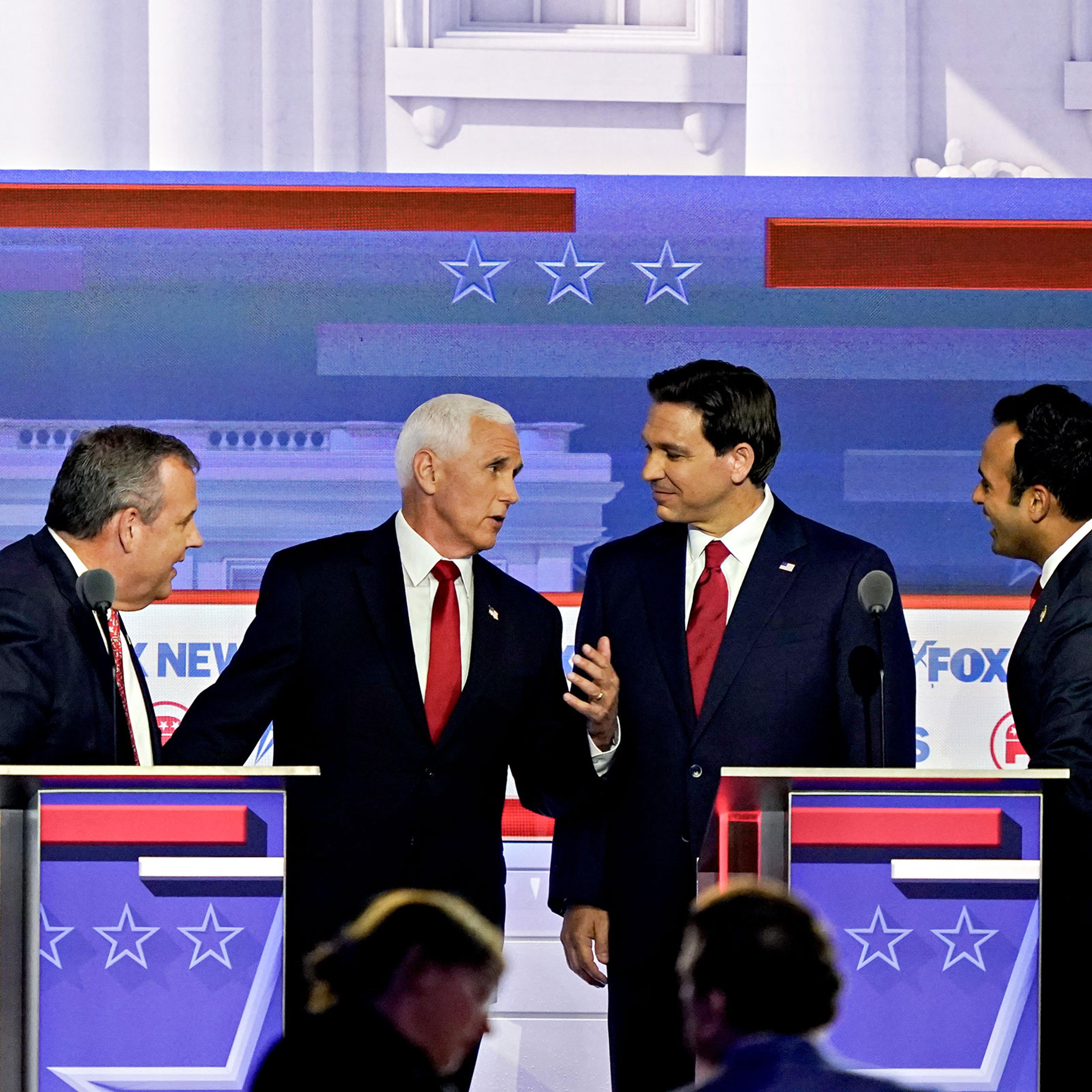 Former governor of N.J. Chris Christie, former Vice President Mike Pence, Fla. Gov. Ron DeSantis, and Vivek Ramaswamy speak to each other away from their podiums during a break at the Republican primary presidential debate in Milwaukee, on Aug. 23, 2023.